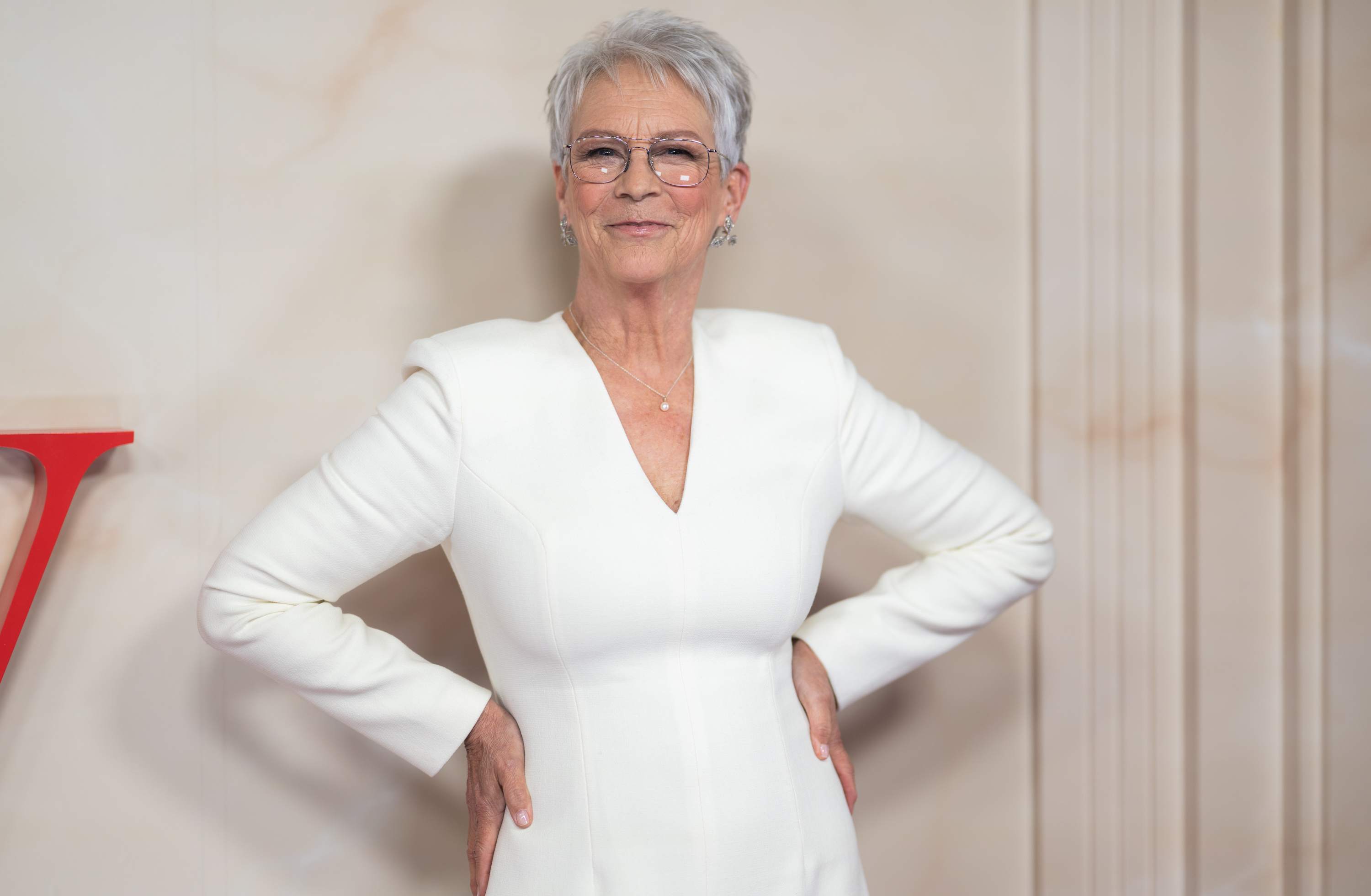 Curtis smiles in a white outfit and glasses at a special screening of "Ella McCay" in London on November 24, 2025. Her short silver hairstyle has become one of her most recognizable looks. | Source: Getty Images