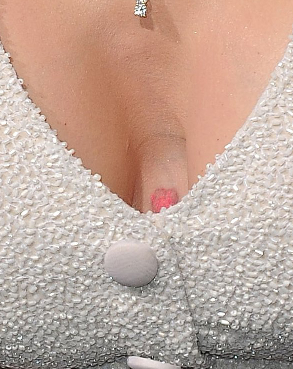 A small pinkish-red tattoo is visible just above the jacket's neckline, offering a rare glimpse of the body art Parton had largely kept out of public view.