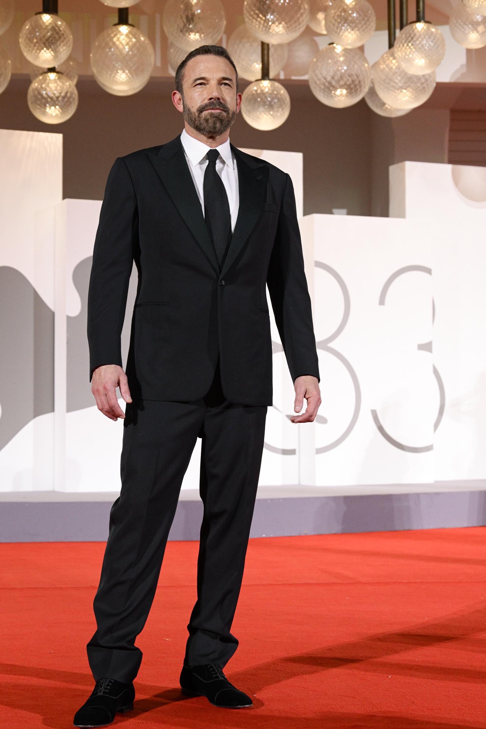 Channeling classic red-carpet tailoring, Ben Affleck chose a single-breasted black tuxedo with peaked lapels, a crisp white dress shirt, and a slender black silk tie at the "Company" screening during the 83rd Venice International Film Festival on September 8, 2026. A trimmed salt-and-pepper beard, neatly combed hair, and understated black dress shoes lent a grounded, distinguished finish to his appearance. | Source: Getty Images