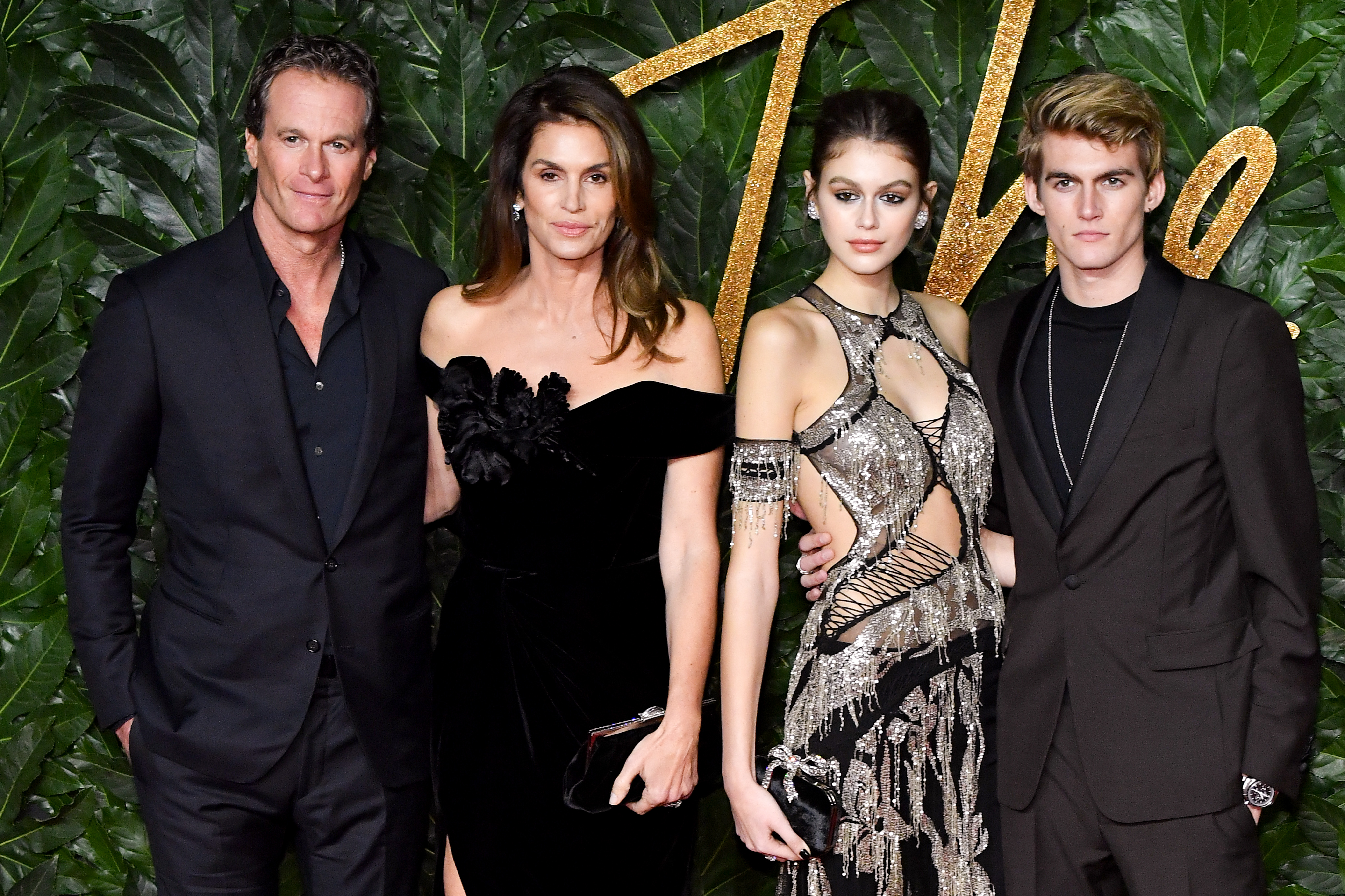 Rande Gerber, Cindy Crawford, Kaia Gerber, and Presley Gerber made a showstopping family appearance at The Fashion Awards 2018 in partnership with Swarovski at the Royal Albert Hall on December 10, 2018, in London, England, posing in sophisticated black-tie attire against a lush green floral wall. | Source: Getty Images