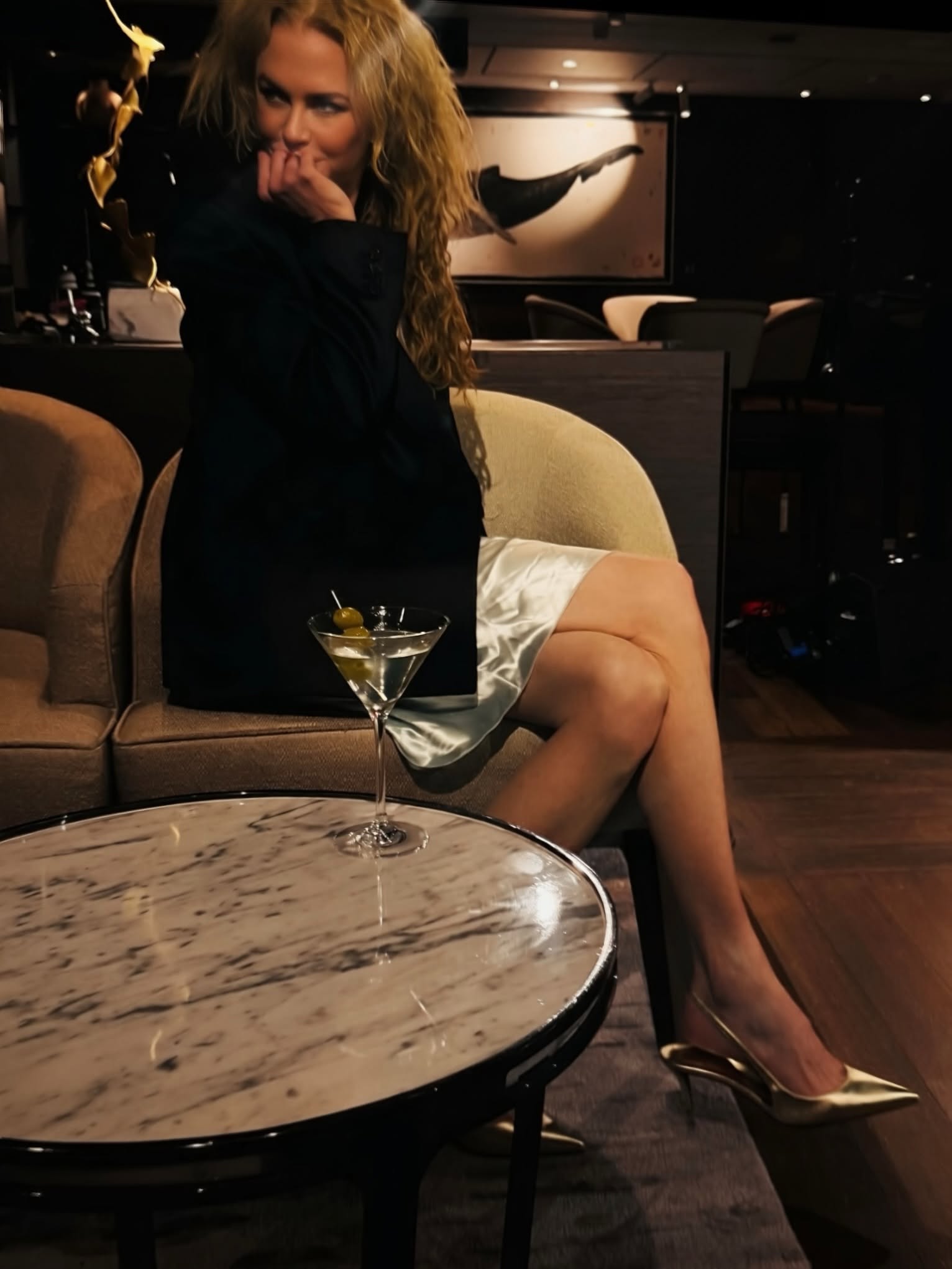 Glamming up for the evening, Nicole sips an olive-garnished martini in a satin slip dress and dark jacket. Metallic heels and soft natural waves completed her effortless night-out look. | Source: Instagram/nicolekidman