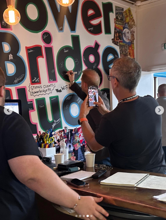 A man records Prince Harry as he signs the celebrity wall at Tower Bridge Studios. The moment came after Harry reportedly spent much of the day at the facility working on an undisclosed project. | Source: Instagram/towerbridgestudios
