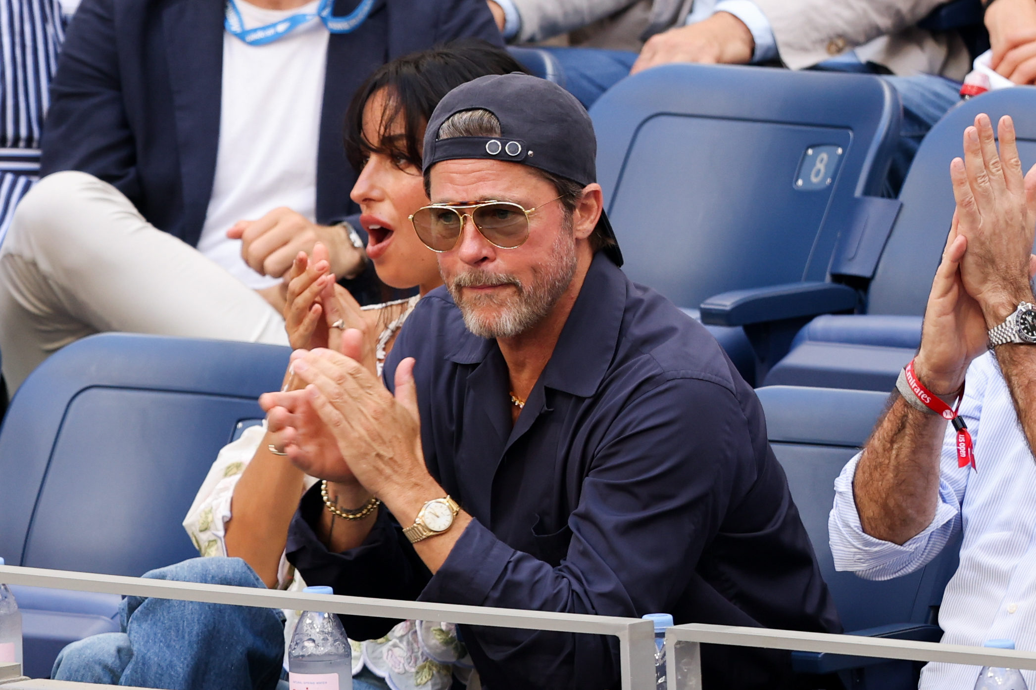 Pitt applauded from the stands as de Ramon reacted to the action behind him. He kept his look casual in navy layers, a backward baseball cap, and gold-framed aviator sunglasses.