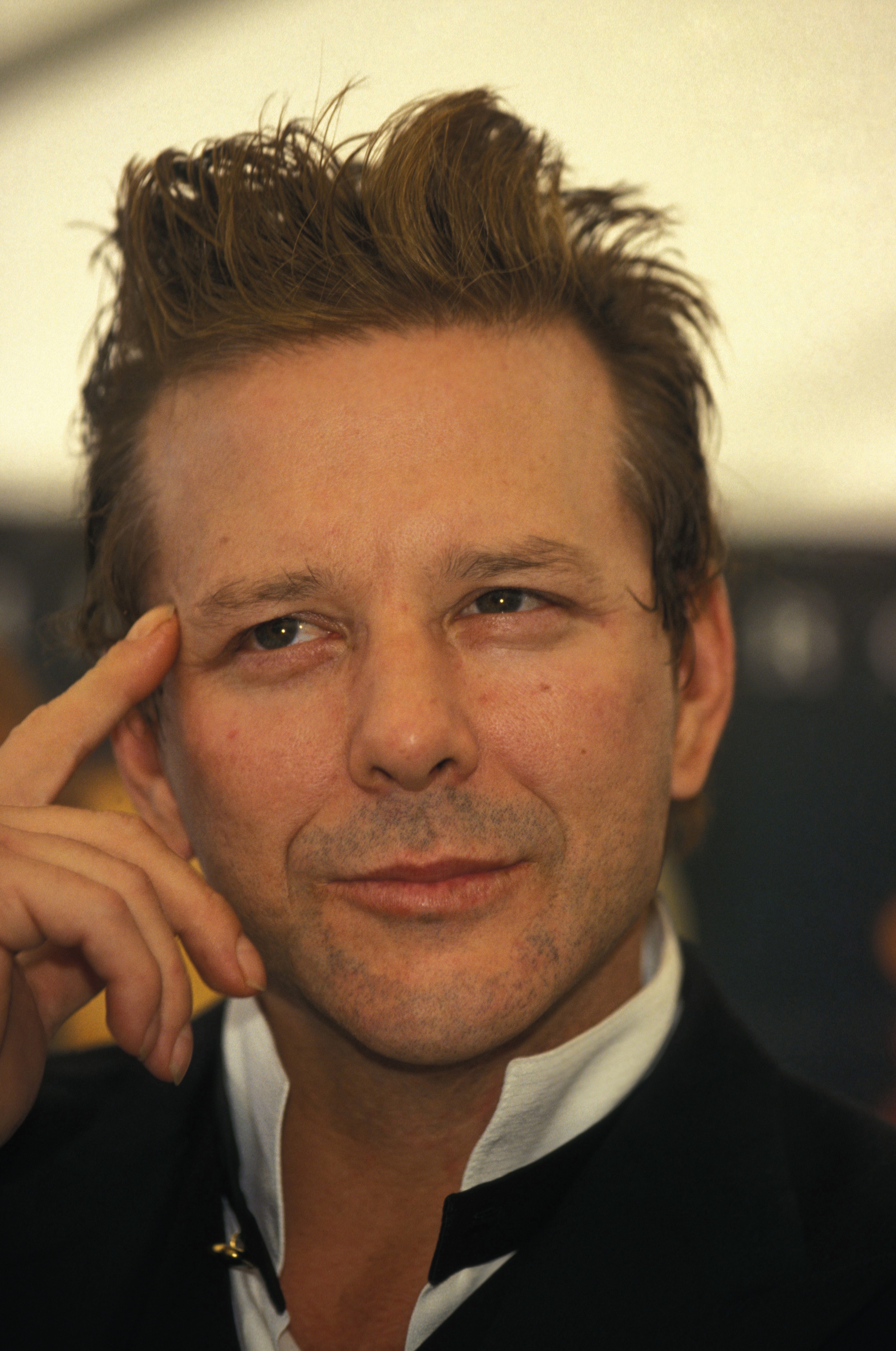 Mickey Rourke strikes a thoughtful pose at the Cannes Film Festival, his expression a mix of charm and quiet intensity. With his tousled hair and sharp attire, he exudes a brooding elegance on the French Riviera stage.