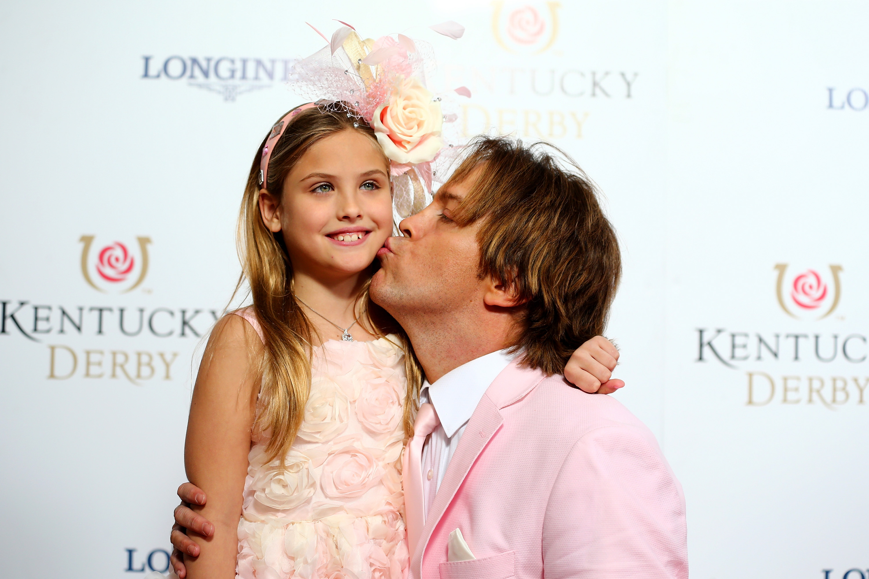 A magnificent pale pink fascinator blooming with a soft rose and delicate feathers crowned 9-year-old Dannielynn Birkhead's cascading blonde hair at the 141st Kentucky Derby on May 2, 2015. Clad in a charming, rose-textured pastel dress, her bright smile and poised demeanor reflected a graceful young girl stepping confidently into her own distinct style at Churchill Downs.
