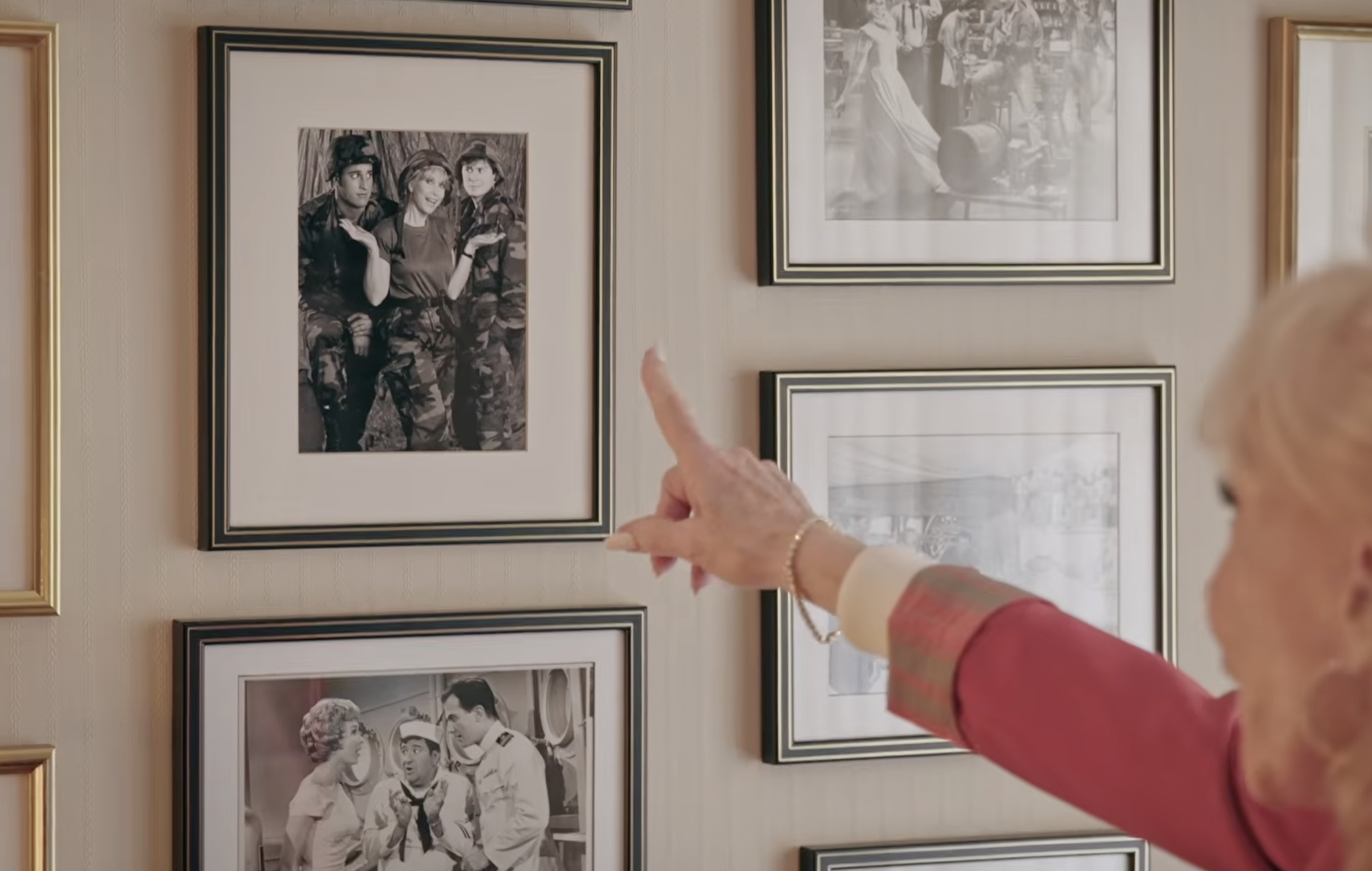 Barbara Eden points toward a framed black-and-white photograph of herself posing between her son, Matthew Ansara, and actor Paul Eiding, who played her son in Your Mother Wears Combat Boots. | Source: YouTube/People
