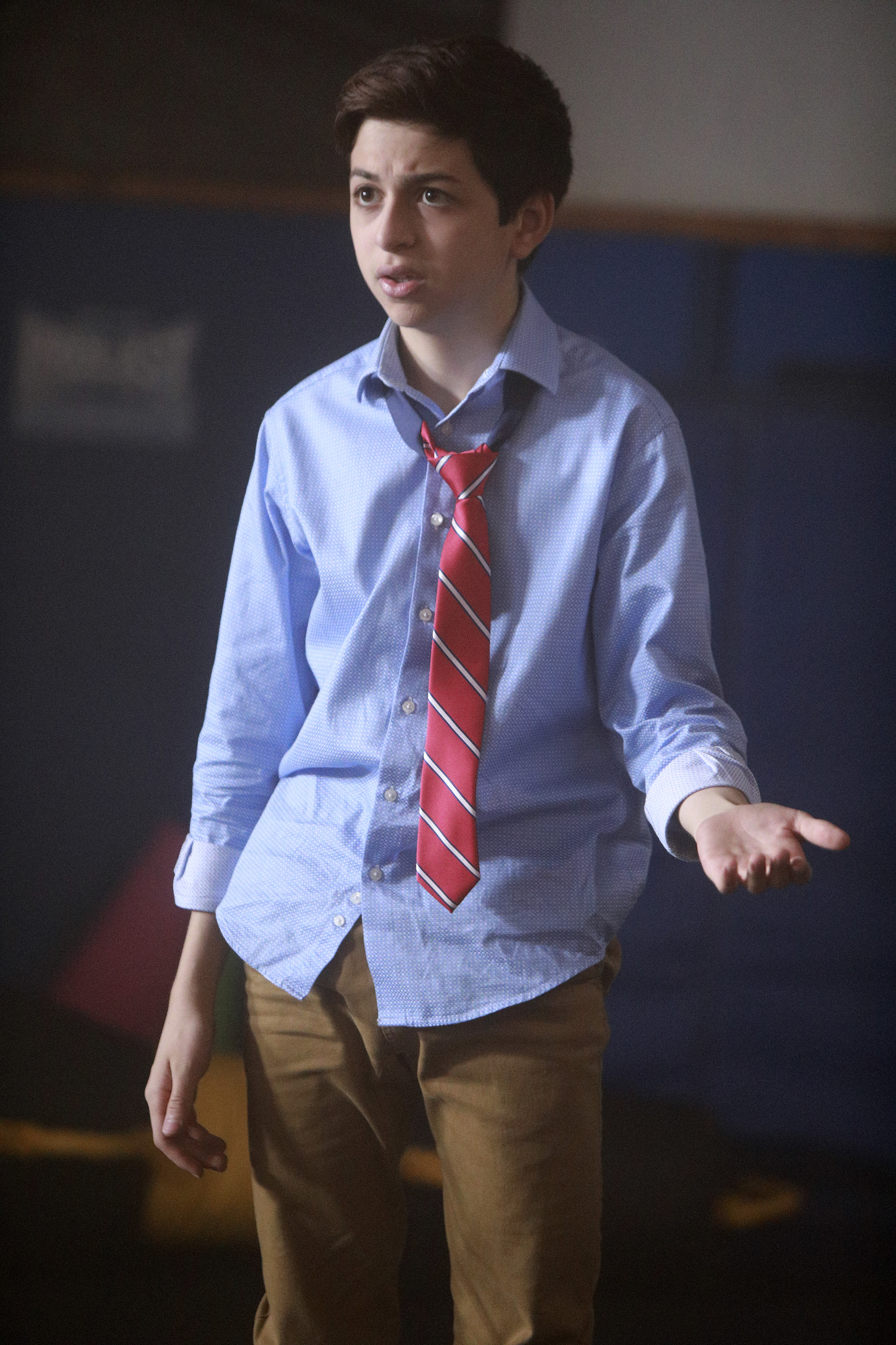 J.J. Totah appears as Michael in Champions, wearing a light blue button-down shirt, a loosely knotted red striped tie, and brown trousers in a scene from the television series. | Source: Getty Images