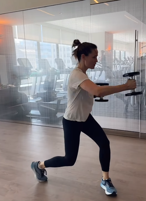 Jennifer Garner wears a white T-shirt, black leggings, and blue sneakers in a modern gym with treadmills visible through a glass wall. | Source: Instagram/jennifer.garner