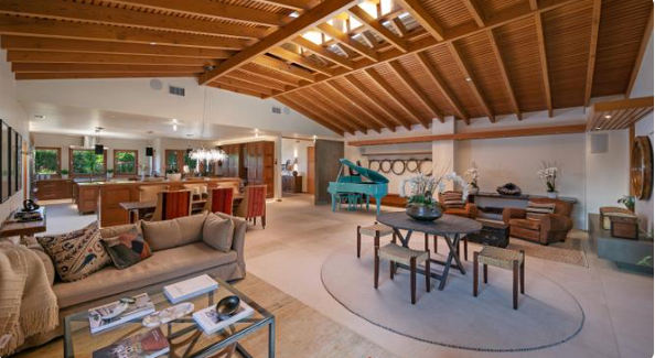 The spacious kitchen features wooden cabinetry, stone countertops, a central island, and large windows overlooking the surrounding greenery. | Source: Redfin