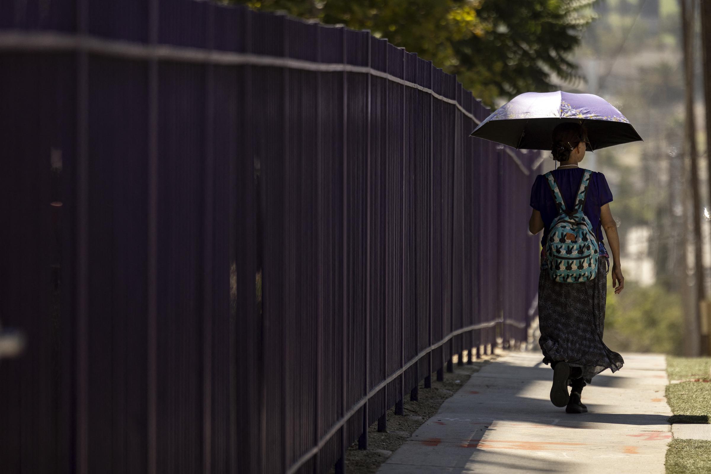 A woman walks under an umbrella for shade as extreme heat scorches Los Angeles, California, on September 4, 2024 | Source: Getty Images