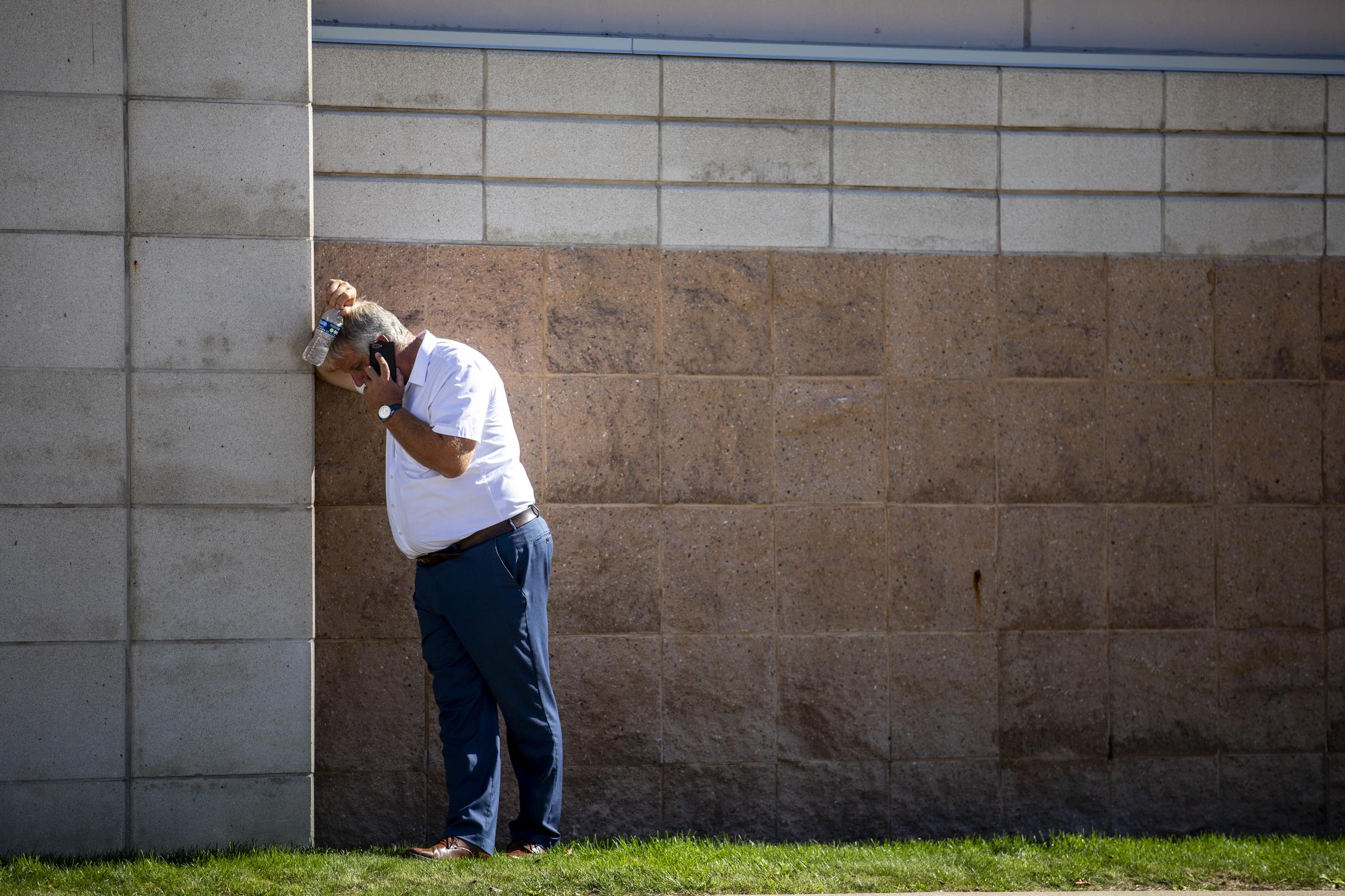A man on his phone looks down as church members and residents reunite at Trillium Theater located across the street from the site of a shooting and fire at the Church of Jesus Christ of Latter-day Saints on September 28, 2025, in Grand Blanc, Michigan. | Source: Getty Images