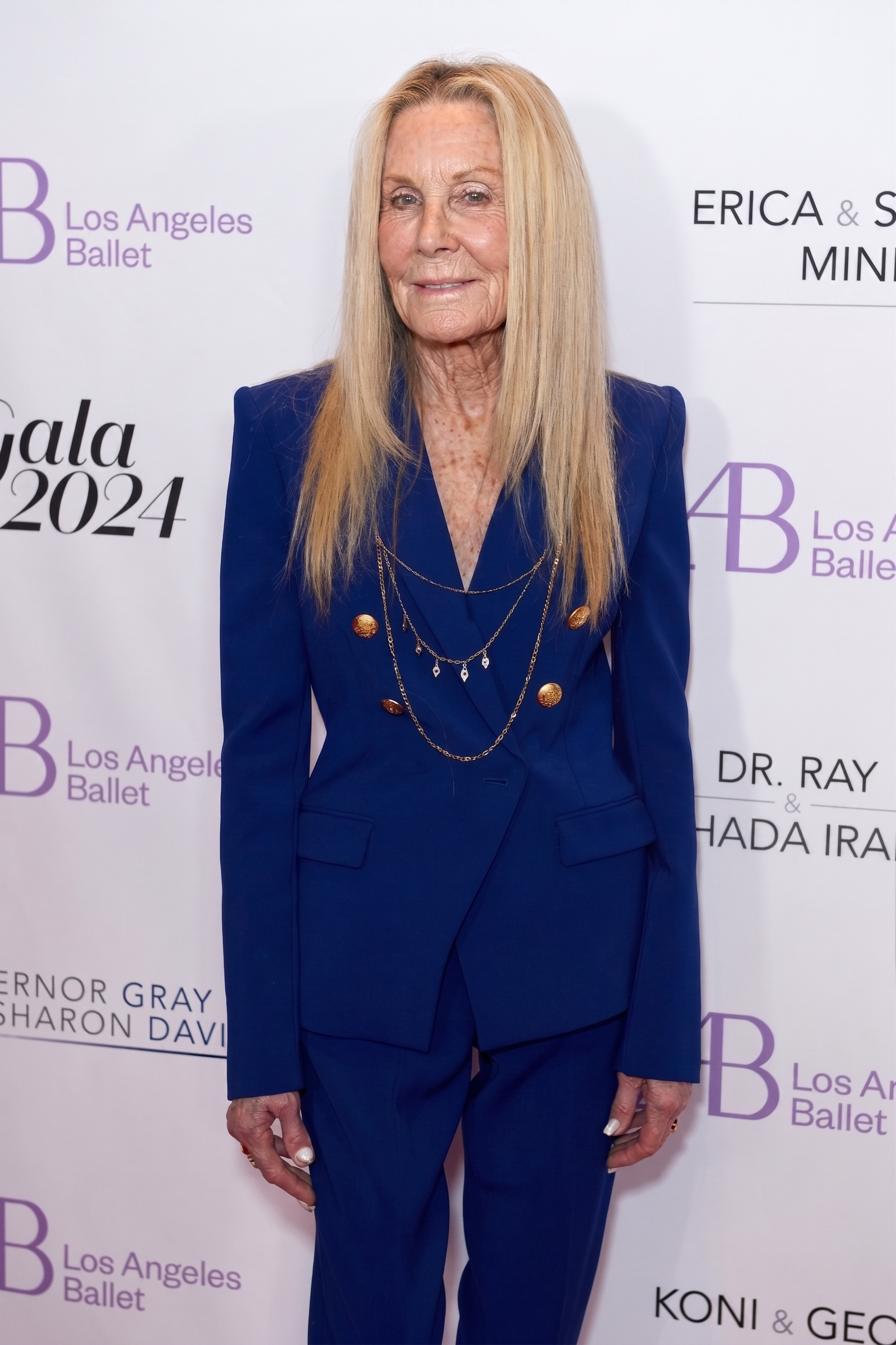 AI envisions Joan Van Ark arriving at a red-carpet event in a tailored blue pantsuit, imagining a version of the actress whose naturally aged appearance complements the timeless elegance and confidence that defined her public image. | Source: Gemini