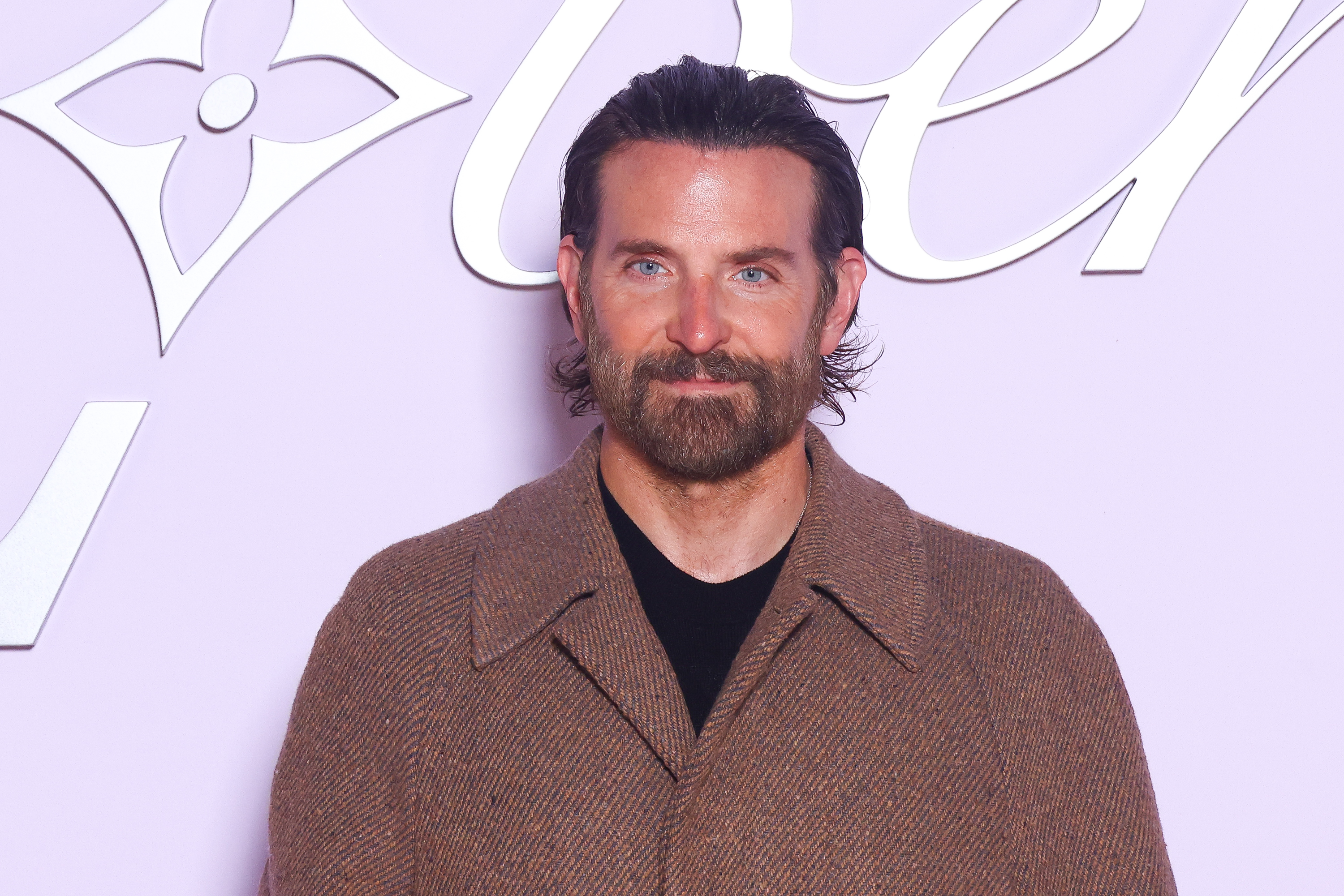 Cooper, now 50, maintained a calm, contemplative expression with subtle lines etching his forehead and surrounding his eyes. He wore a full, well-groomed beard, showing a blend of brown and gray, with his dark brown hair pulled back and resting over his ears as he attended the Louis Vuitton Menswear Fall-Winter 2025/2026 show as part of Paris Fashion Week on January 21, 2025, in Paris, France.