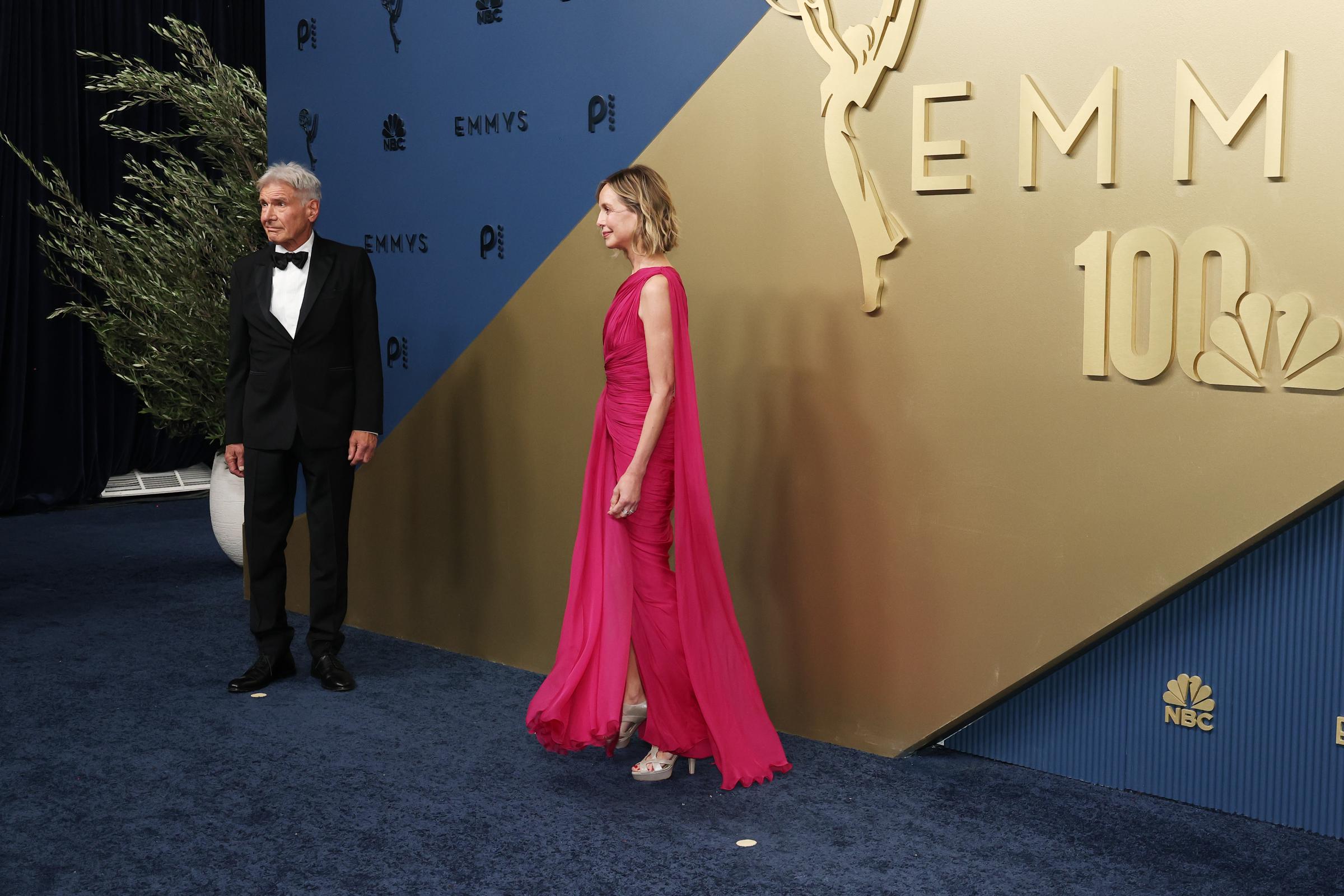 Flockhart steps onto the arrivals carpet in a vivid fuchsia gown as Ford stands nearby in classic black tie. Her one-shoulder design featured gathered detailing and fabric that flowed down her back.