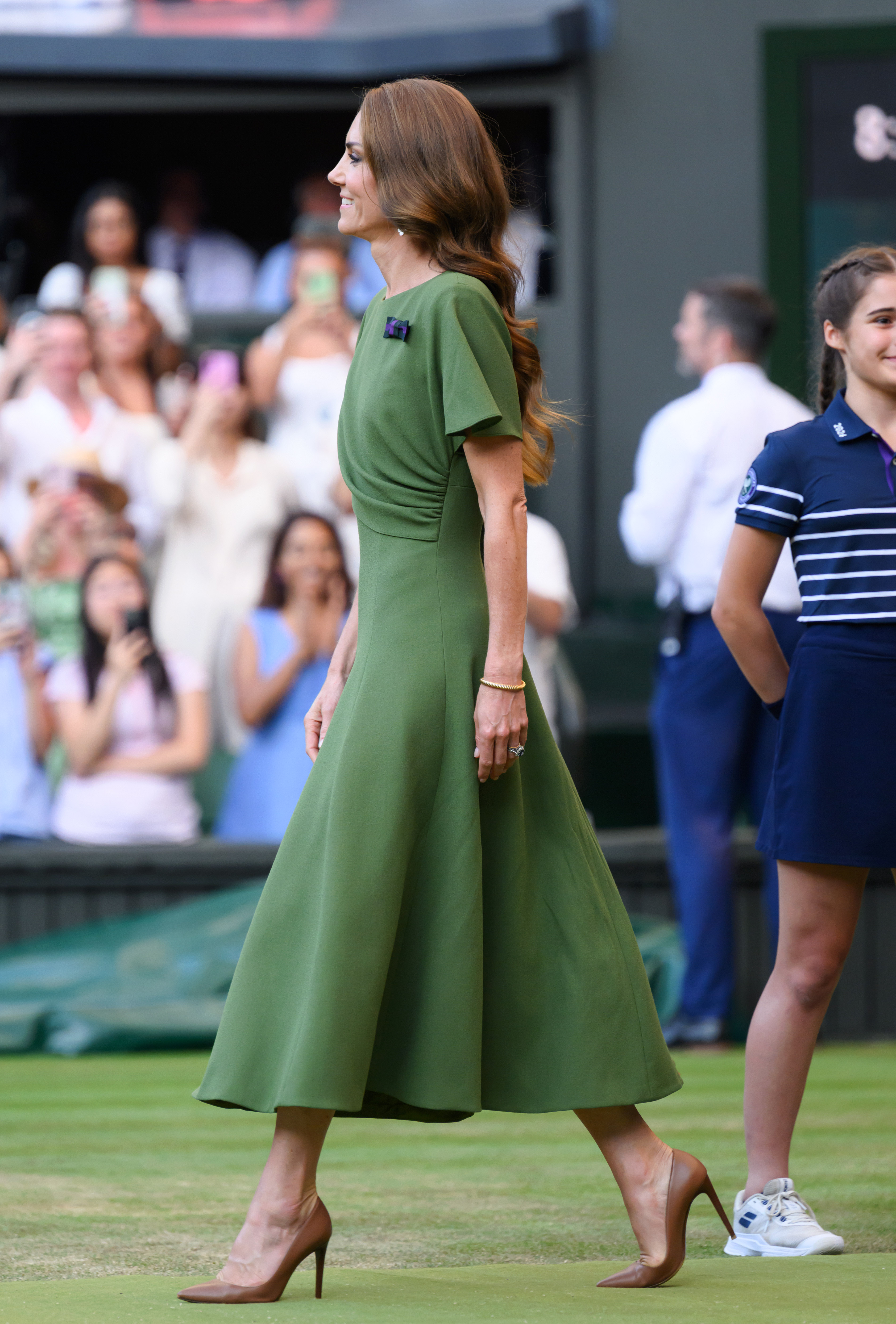 From the side, the dress shows its soft draping and cape-style sleeve, giving the outfit graceful movement as Catherine walked across the court. The olive-green shade complemented the famous Wimbledon setting. | Source: Getty Images