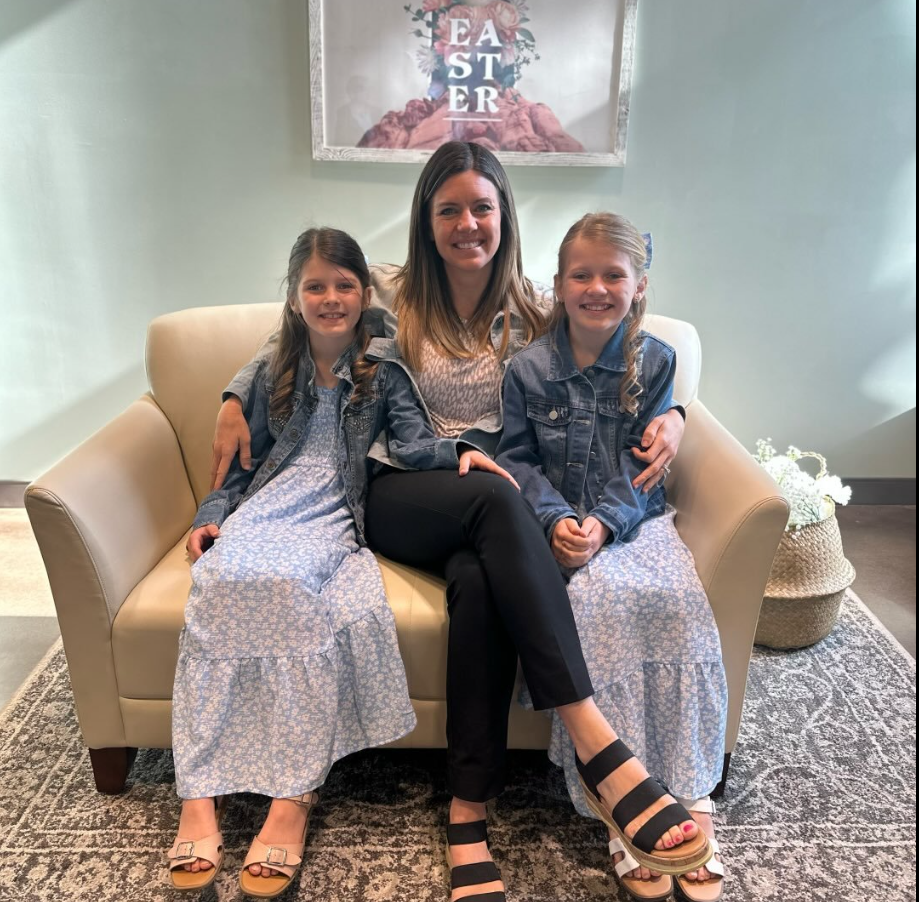 Ashley Flynn is seated in a light-colored armchair with her two young daughters sitting closely on either side of her. | Source: Facebook/AshleyFlynn