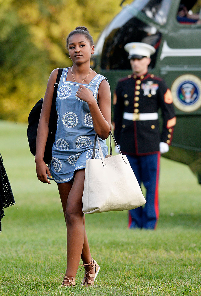 Sasha Obama, wearing a sleeveless blue printed dress and sandals, walked across the South Lawn with a backpack over one shoulder and a cream handbag in hand after stepping off Marine One from the family's return from Martha's Vineyard.