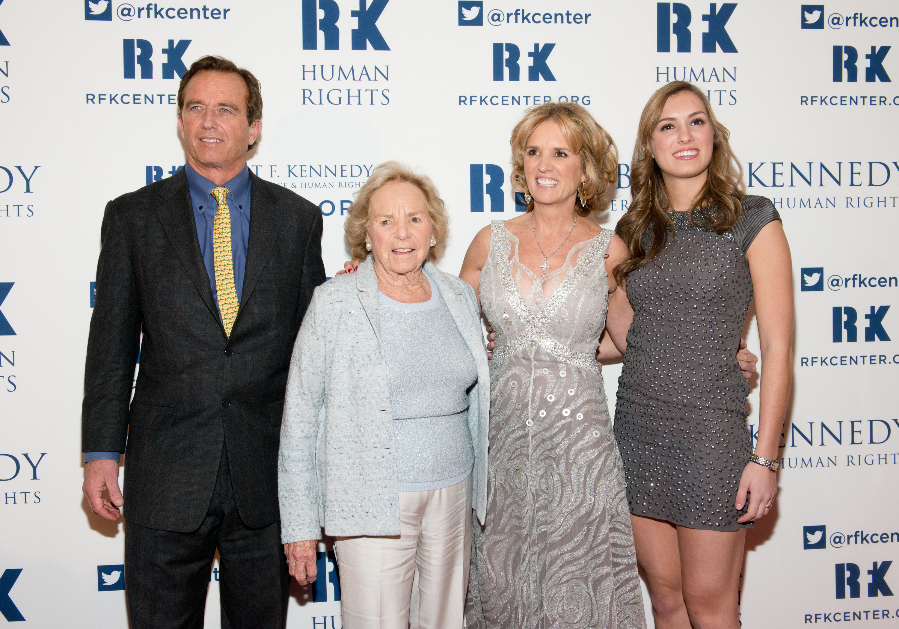 Robert F. Kennedy Jr., Ethel Kennedy, Kerry Kennedy, and Kyle Kennedy pose together at the 2013 Ripple of Hope Awards Dinner at the New York Hilton on December 11, 2013, in New York City. Robert stands in a dark suit with a yellow patterned tie beside family matriarch Ethel Kennedy in an icy blue knit set, while Kerry shines in a beaded silver-grey gown alongside Kyle, who smiles in a fitted grey sleeveless mini dress accented with embellishments. | Source: Getty Images
