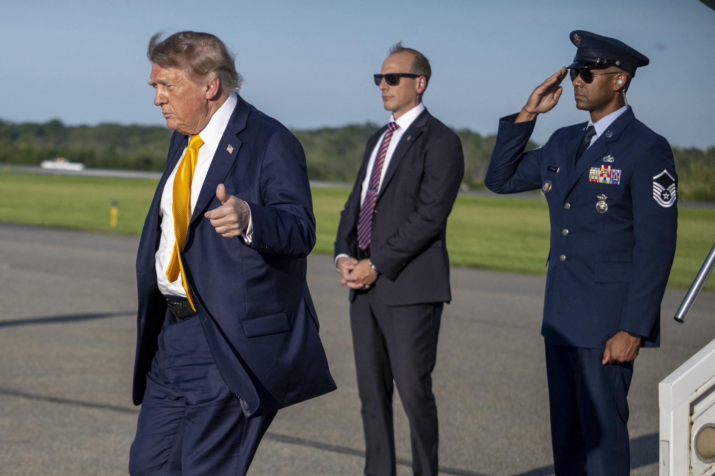 The president flashes a thumbs-up as he heads toward his weekend at his Bedminster golf club, with the evening light highlighting the dramatic change in his hair color.