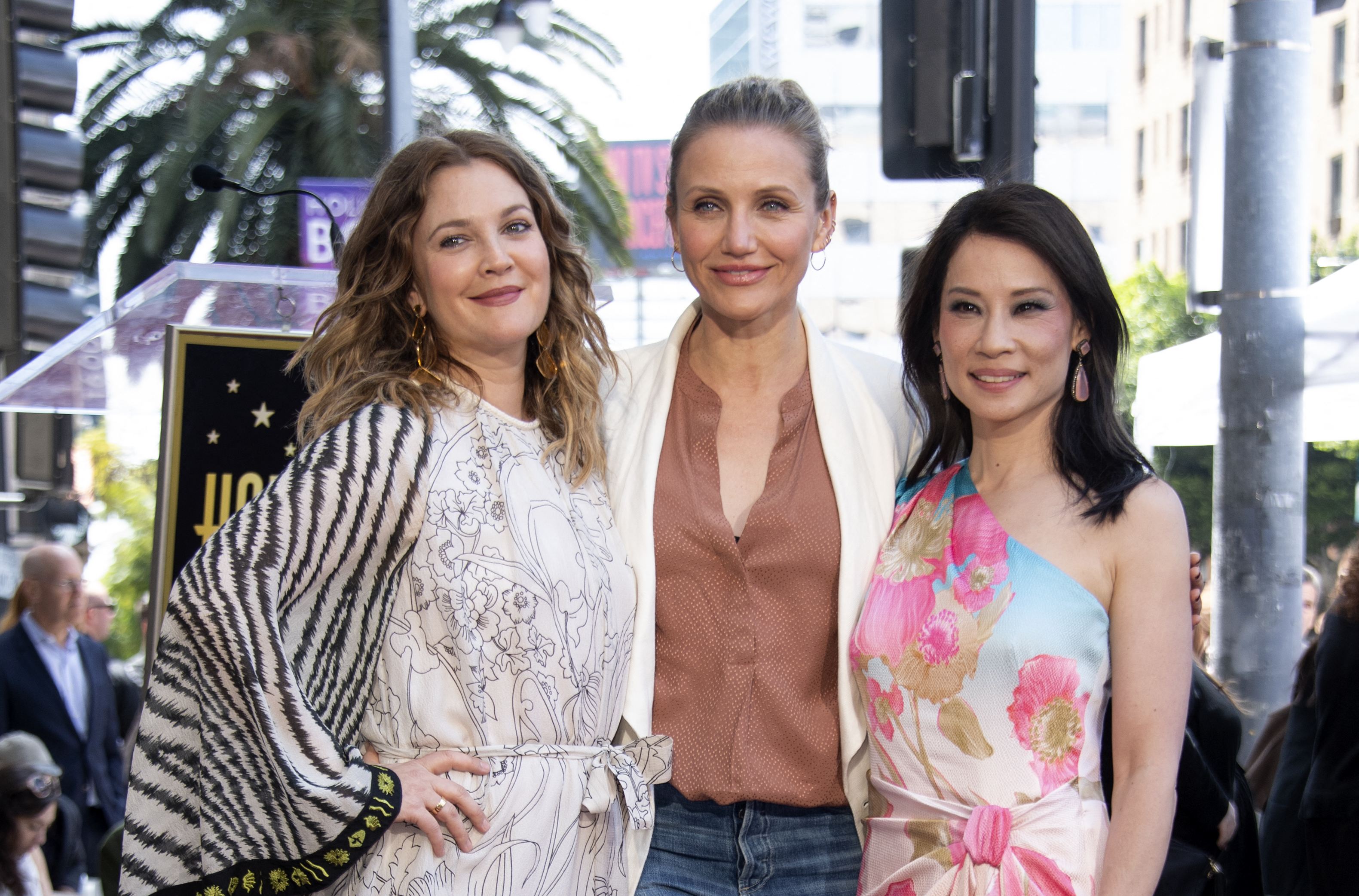 Drew Barrymore, Cameron Diaz, and Lucy Liu stand together at Lucy Liu’s Hollywood Walk of Fame ceremony, smiling for photos as they pose side by side in coordinated, elegant outfits.