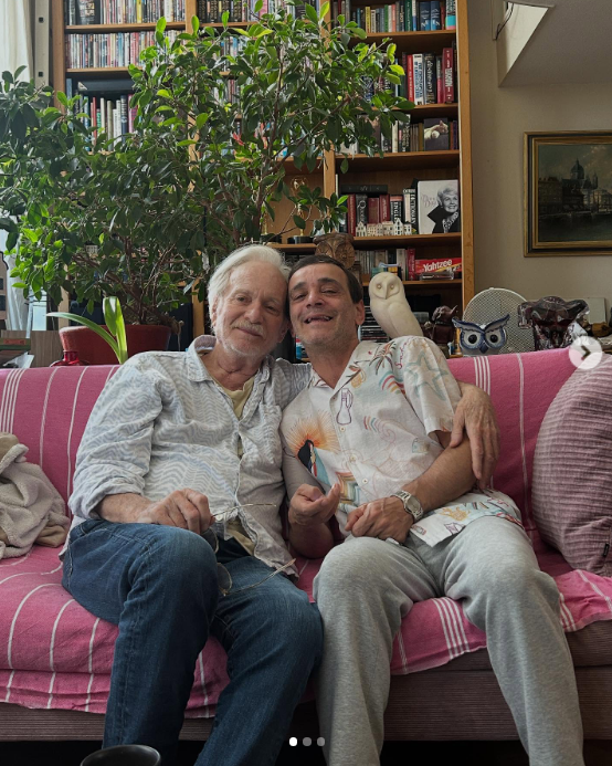 Anthony Geary and his husband Claudio Gama sitting on a sofa in their home in Amsterdam, from a post dated September 23, 2025 | Source: Instagram/claudiogama_71
