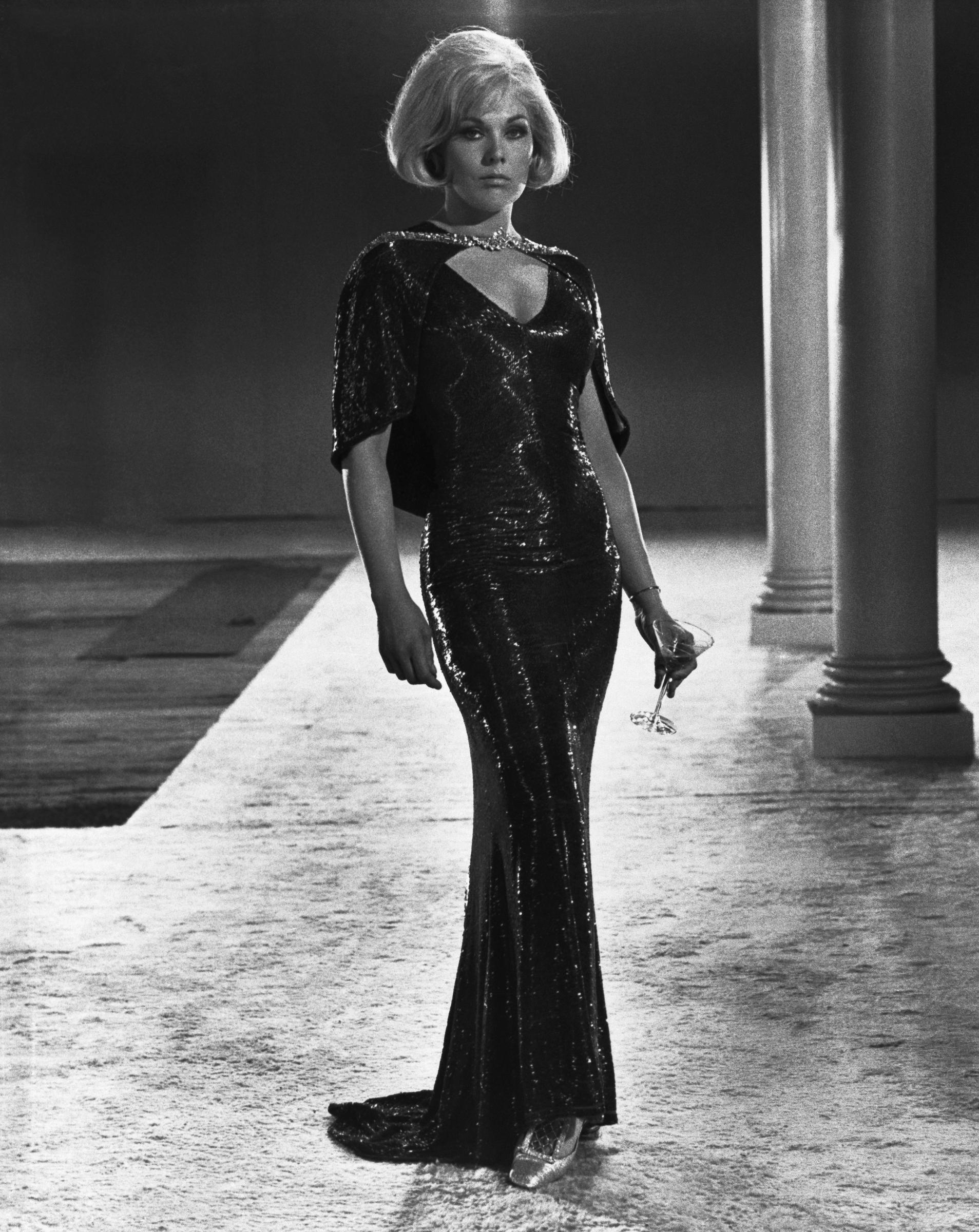 Kim Novak wears a sparkling black evening gown with a matching cape in a scene from The Legend of Lylah Clare. | Source: Getty Images