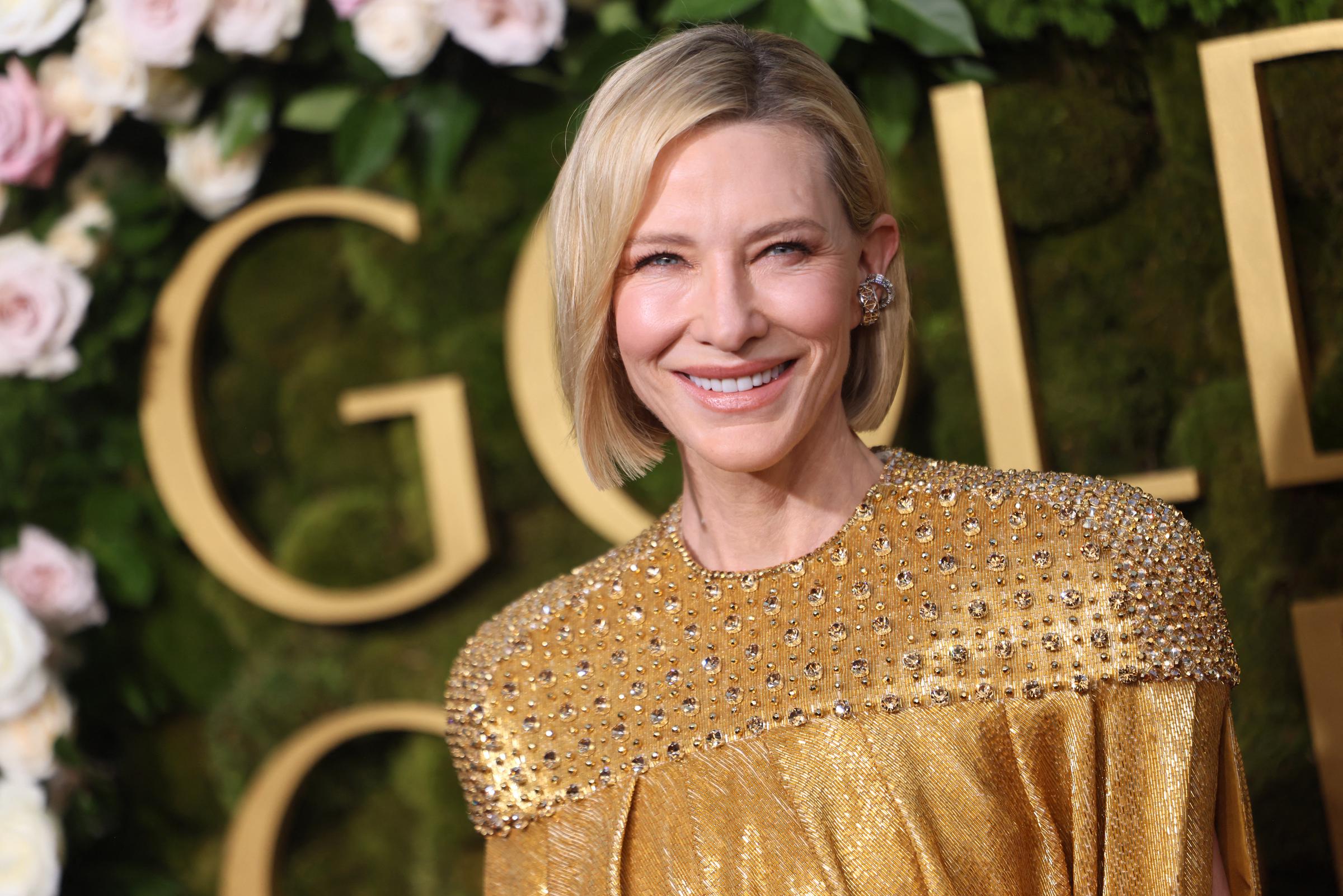 Cate Blanchett arrives at the Golden Globe Awards in Beverly Hills, posing against a floral backdrop with large event lettering | Source: Getty Images