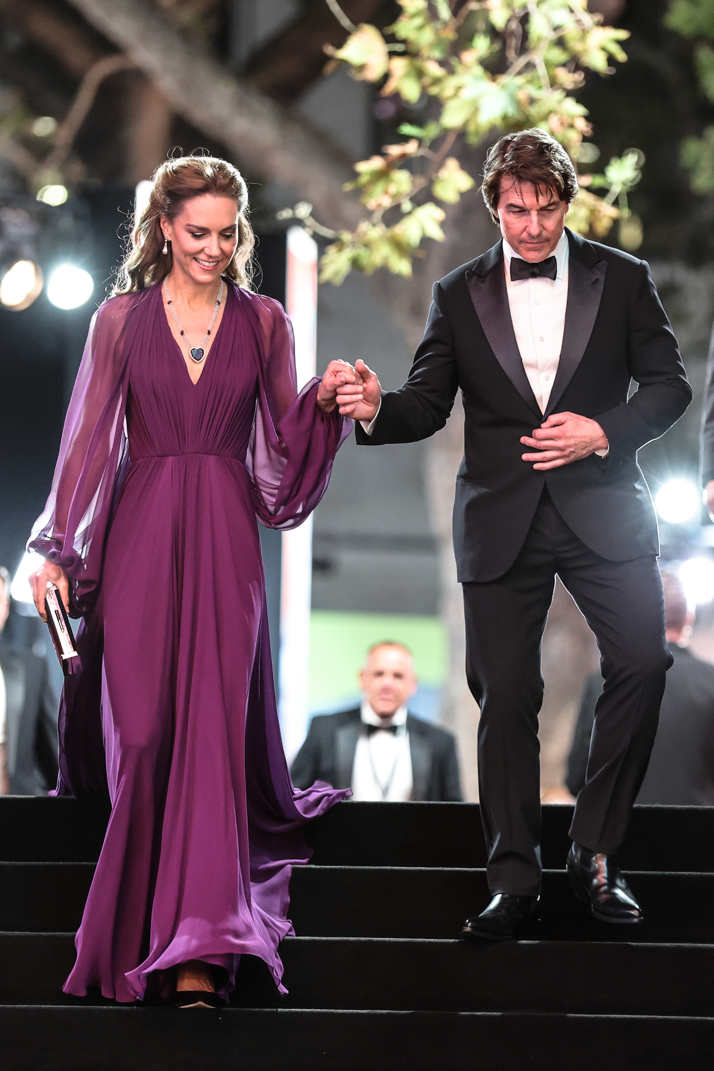 Tom holds Catherine's hand as the pair descend the steps, with the princess managing the long hem of her gown in her other hand. The gesture became one of the moments social-media users singled out from the premiere.