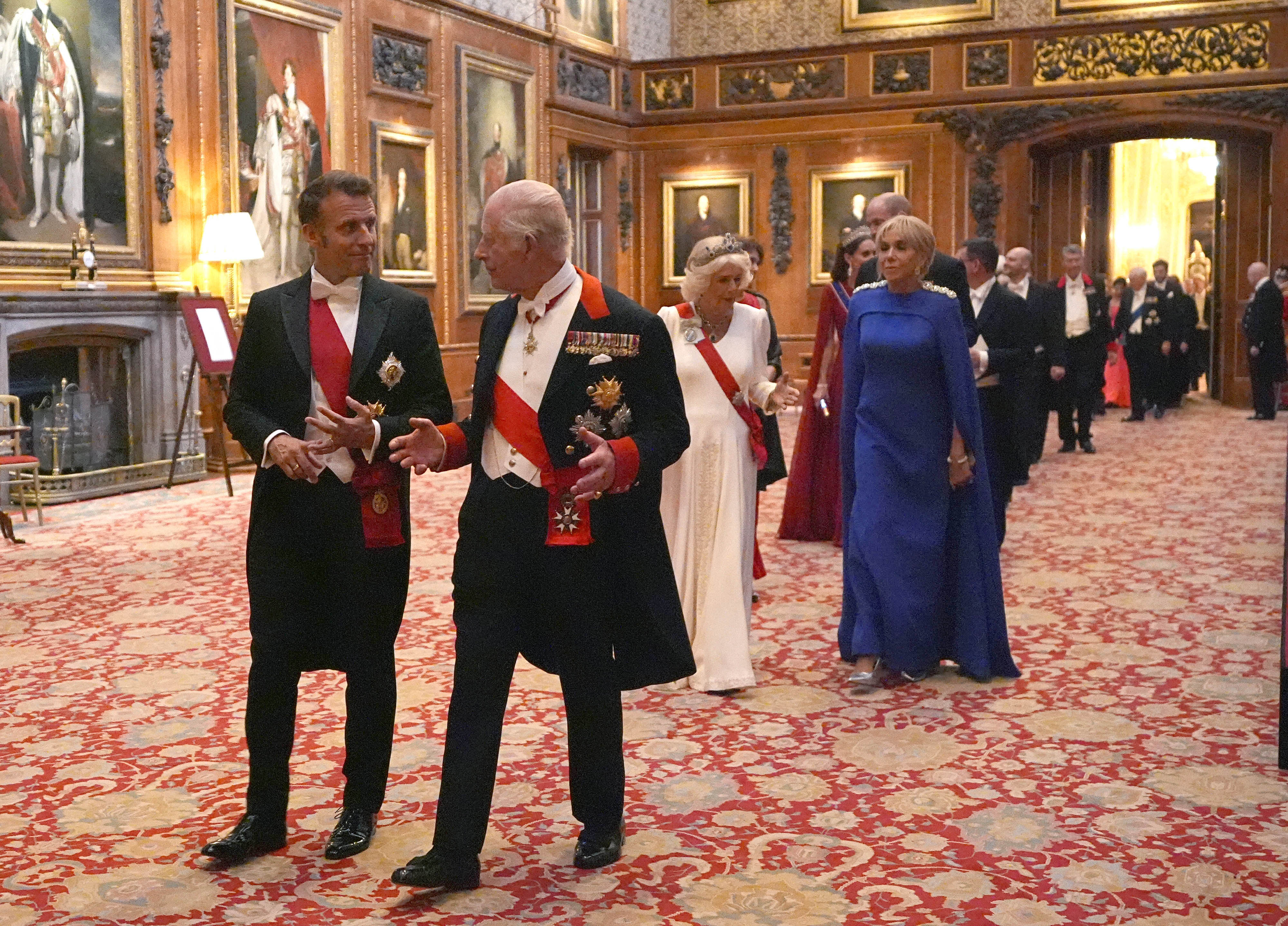 King Charles III with President of France Emmanuel Macron walk the halls of the castle to the banquet hall. They are followed by Queen Camilla and First Lady of France, Brigitte Macron who also attend the state banquet in London.