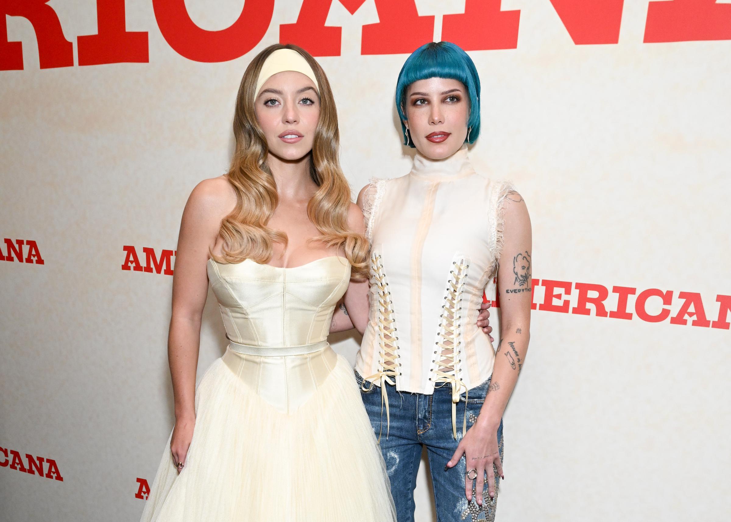 Sydney Sweeney poses beside Halsey in this shot, her ivory gown nearly fully visible. The soft tulle skirt cascades into view, while the structured bodice and headband remain focal points. Standing close, the pair strike a relaxed pose, blending glam with effortless charm.