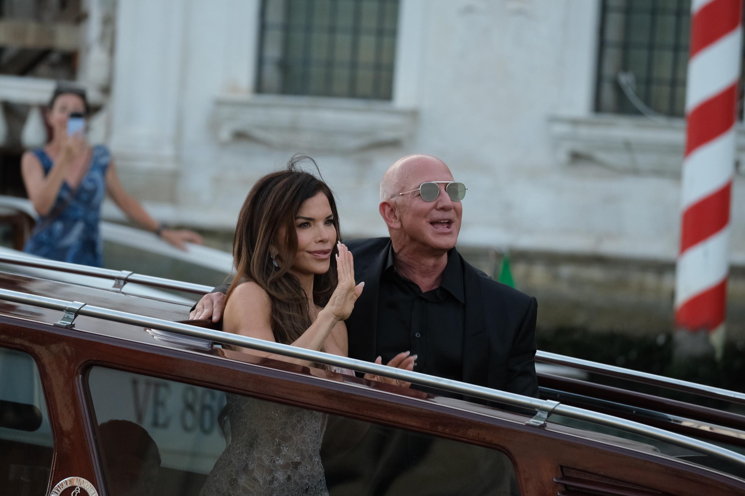 Lauren Sánchez and Jeff Bezos waving to onlookers from a boat during their wedding celebration | Source: Getty Images