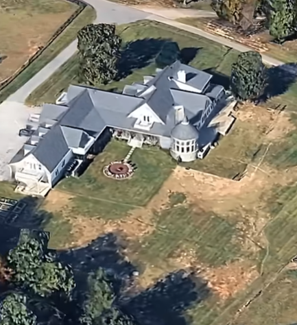 From this angle, the home's connected wings and rounded exterior feature are easier to see. The surrounding grass, trees, and nearby road provide a clearer sense of the residence's footprint. | Source: Youtube/HouseOfCelebs