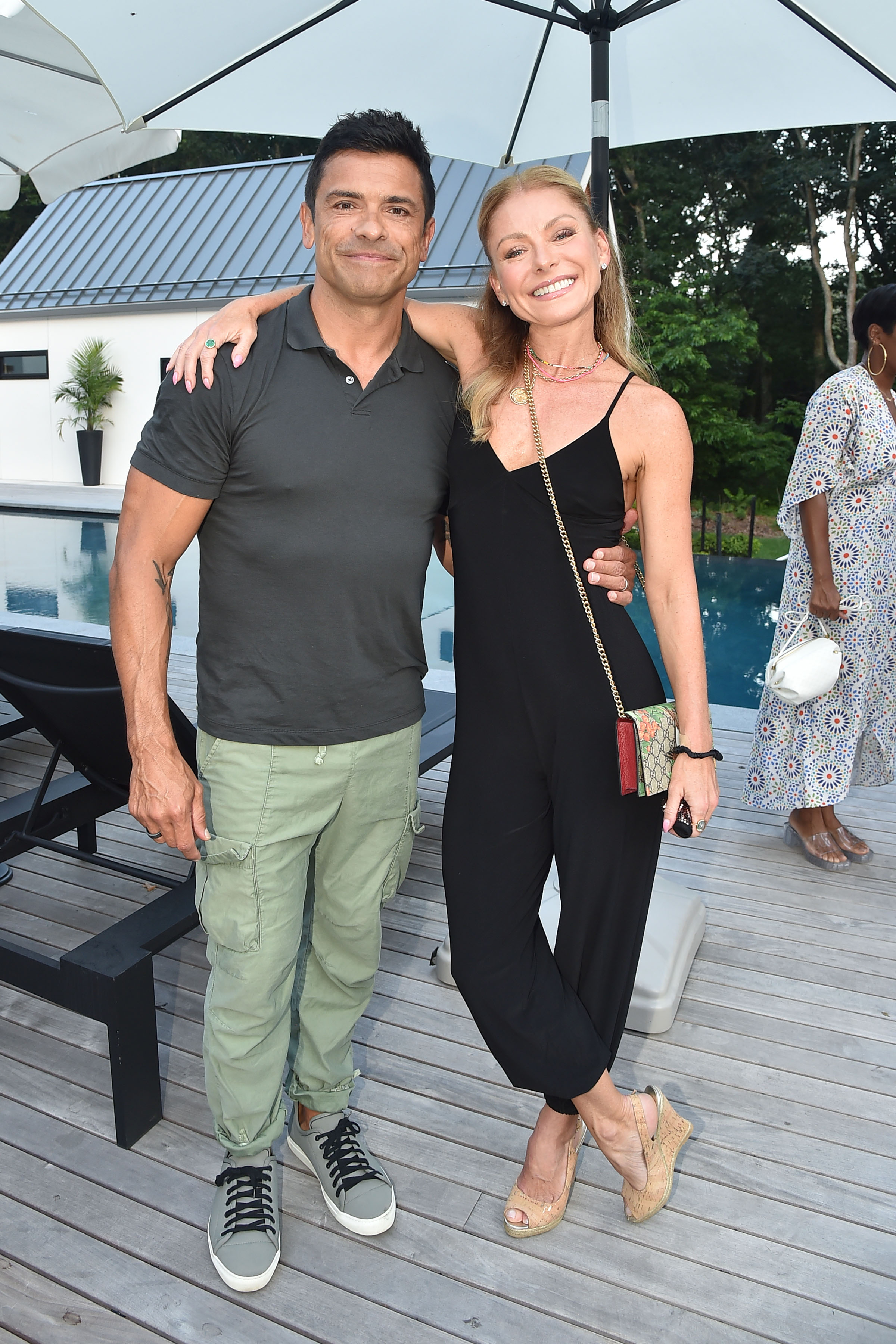 Kelly Ripa and Mark Consuelos share a sweet moment as they pose together at an outdoor event, with Kelly wrapping her arm around her husband. | Source: Getty Images.