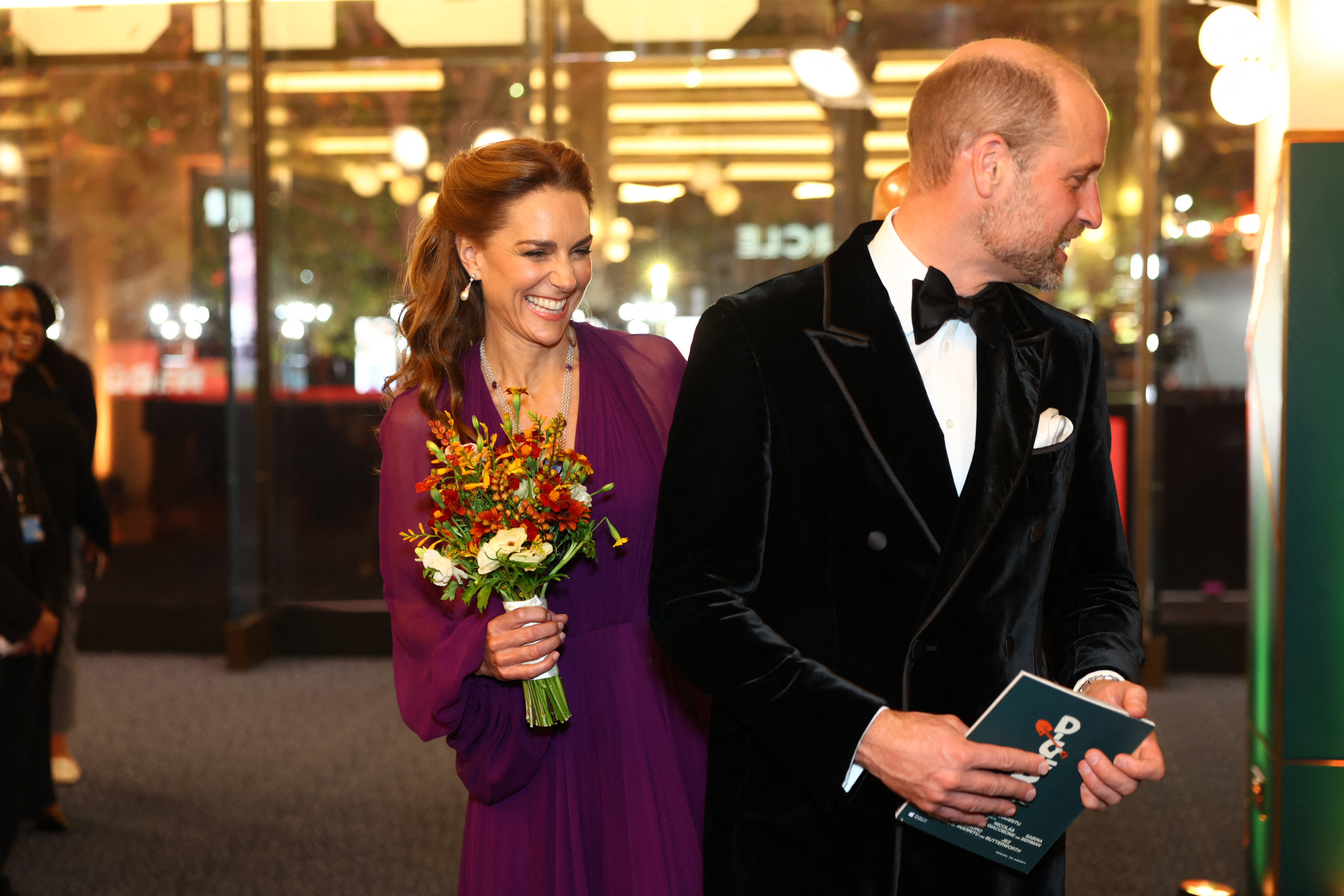 Catherine walks beside William while carrying a colorful bouquet at the "Digger" global premiere in London's Leicester Square. William wears a black tuxedo as the pair are photographed together during the September 22 event.