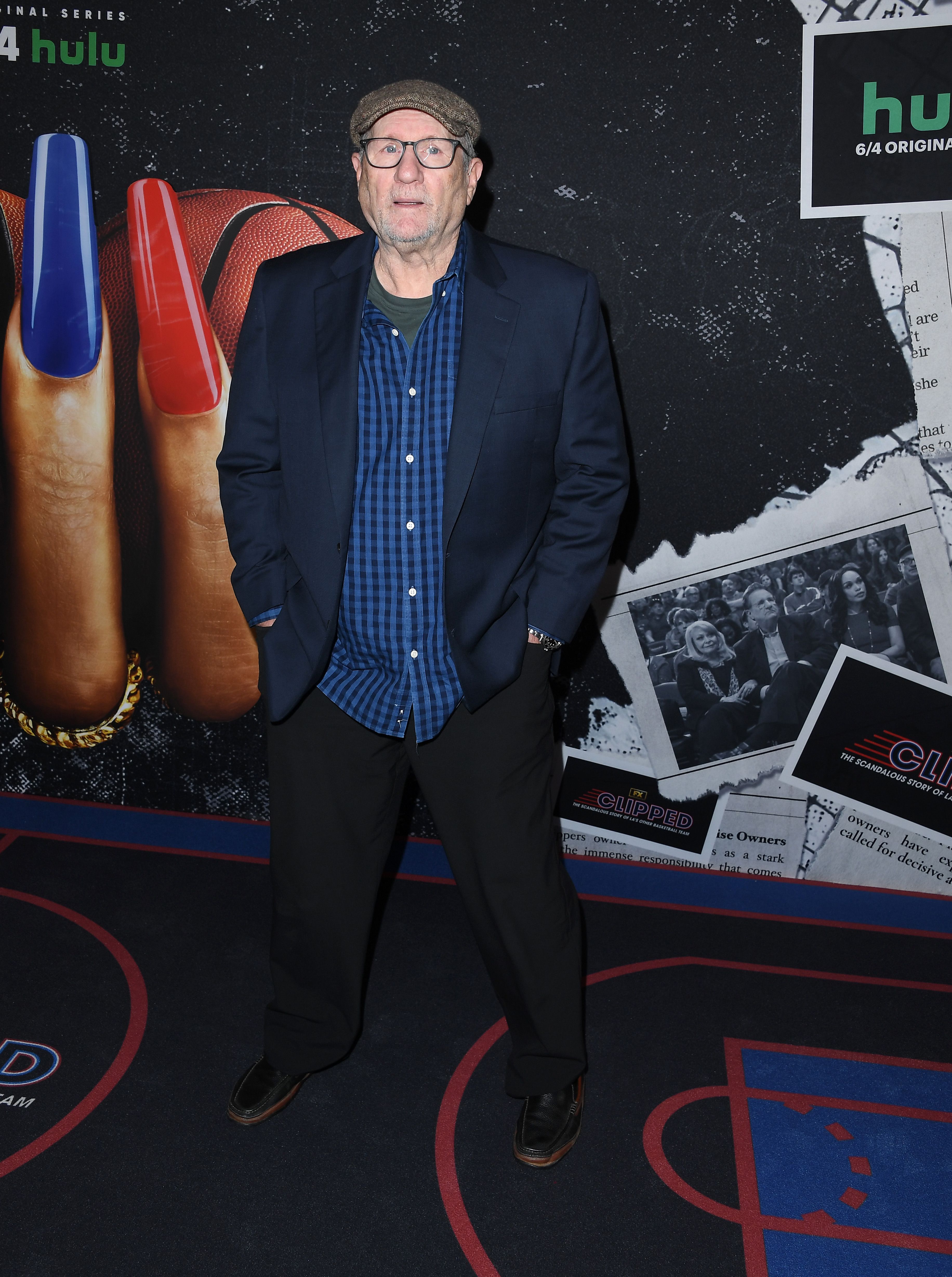 Ed O'Neill struck a relaxed pose on the red carpet for the Los Angeles premiere of FX's "Clipped" at Regal LA Live on June 3, 2024, in Los Angeles, California. The veteran actor—who portrays former LA Clippers owner Donald Sterling in the limited series—wore a navy blazer layered over a blue gingham button-down shirt, paired with black trousers, clear-framed glasses, and a classic tweed flat cap. | Source: Getty Images