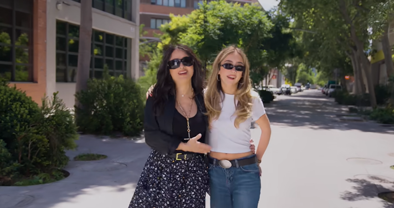 Salma and Valentina walked arm in arm before continuing their vintage-shopping trip. Their contrasting outfits reflected the style differences they discussed, with Salma choosing a dark floral skirt and Valentina wearing a white cropped T-shirt with loose jeans. | Source: Youtube/instagram