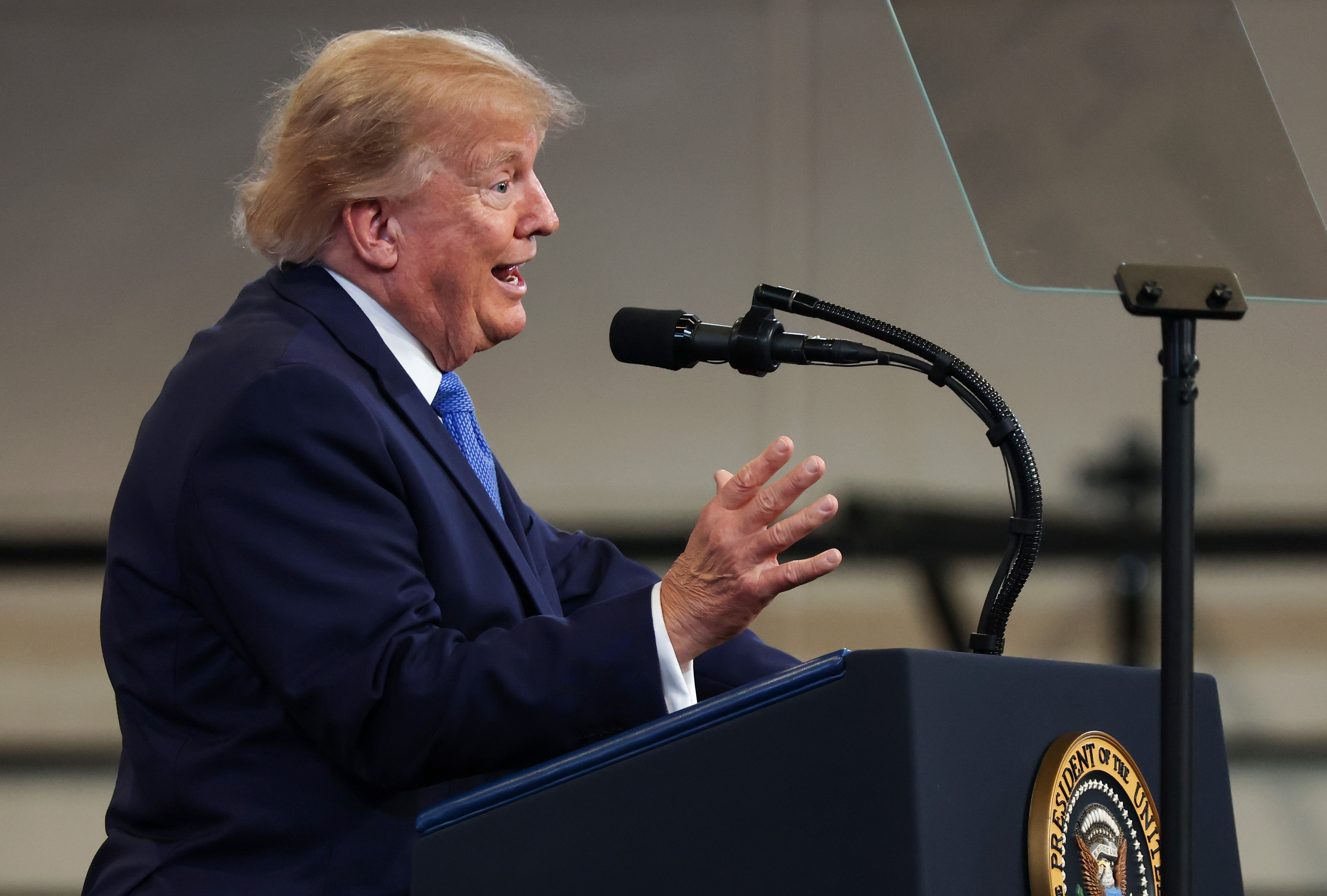 Donald Trump's hair appears golden blond with lighter gray strands as he delivers remarks at the David S. Mack Center for Training and Intelligence in Garden City, New York, on August 14, 2026.