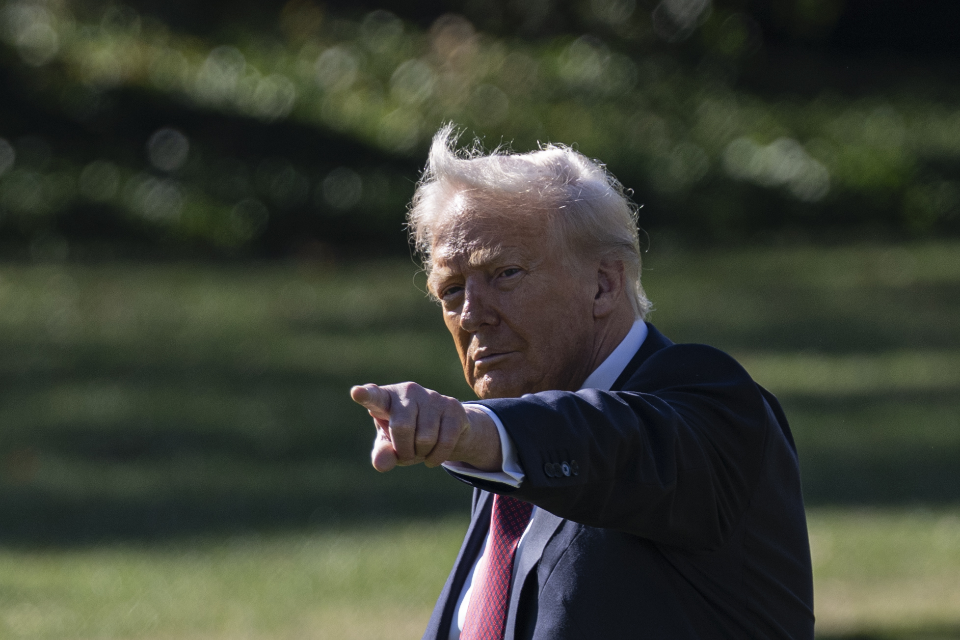 Donald Trump's hair appears pale blond with prominent gray tones as the wind lifts his familiar swept style while he departs the White House for Miami on November 5, 2025.