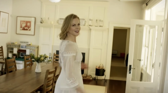 The farmhouse dining room features a long wooden table surrounded by classic ladder-back chairs, all set beneath soft wall paneling and natural light pouring in through French doors. From a video dated July 20, 2015. | Source: YouTube/Vogue