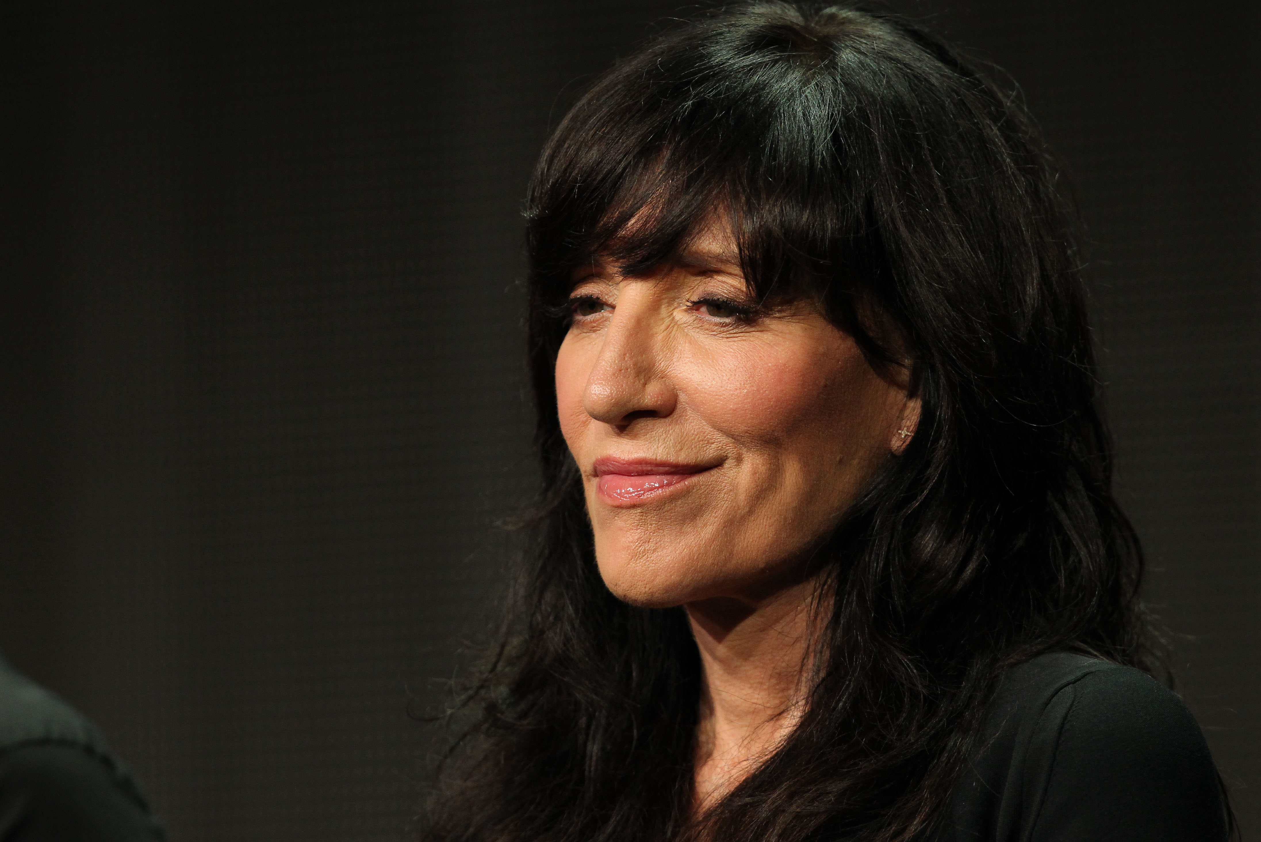 Katey Sagal smiled subtly while speaking during the panel for FX's "The Bastard Executioner" at the Summer TCA Press Tour on August 7, 2015, in Los Angeles, California. Wearing her dark brunette hair down in soft waves with fringe, the actress sported a simple black top and minimal accessories as she discussed her role in the historical drama series. | Source: Getty Images