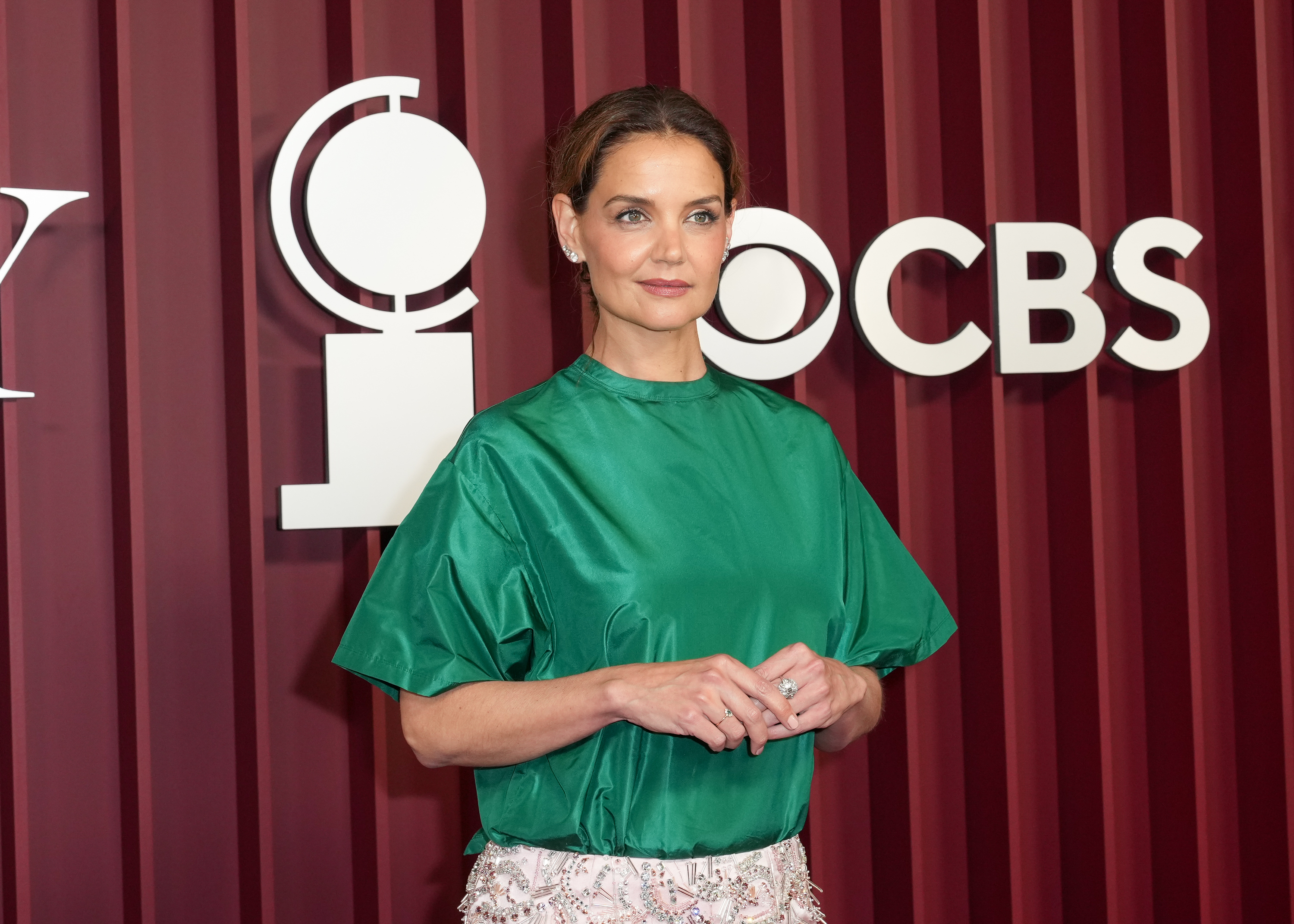 Wearing a bold color combo, Katie Holmes appears poised in green satin and soft-toned makeup, standing in front of the CBS and Tony logos as she arrives to present at Broadway's biggest night in New York City.