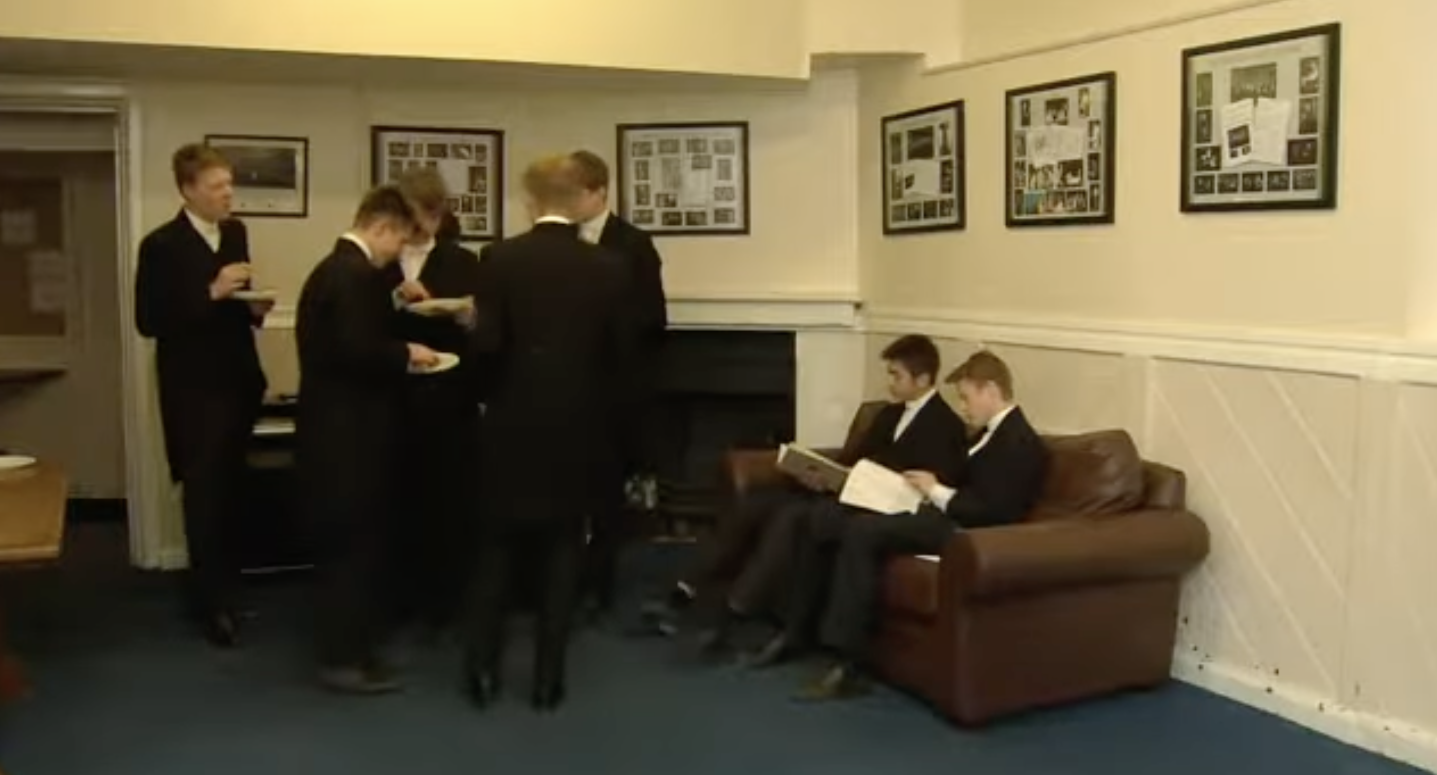 Students gather in a communal lounge furnished with a brown sofa, fireplace, and framed pictures. The shared space offers a glimpse of life beyond Eton's individual bedrooms. | Source: Youtube/Paradoxyy