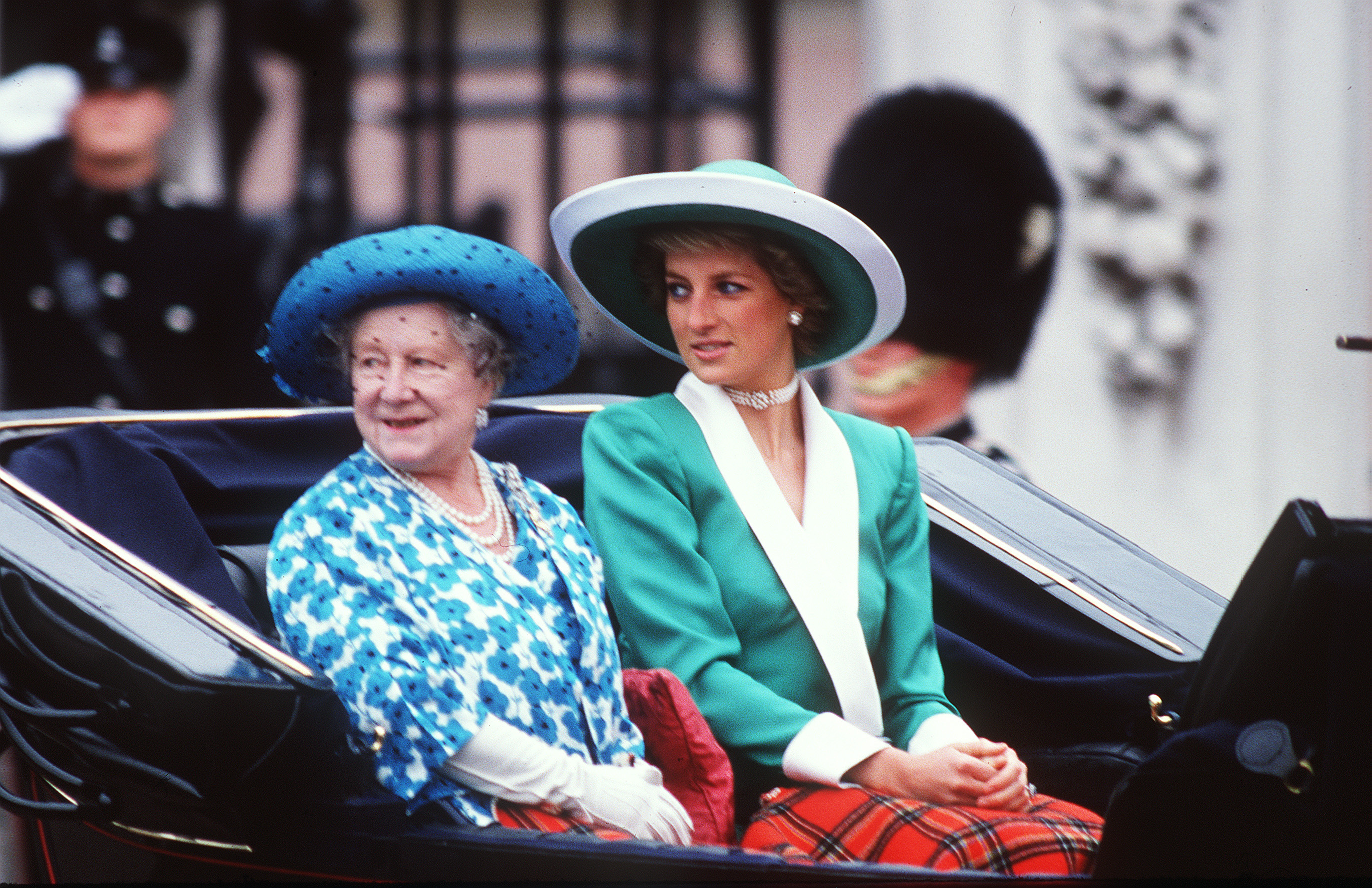 Diana, Princess of Wales, rides alongside the Queen Mother in the carriage procession during the 1988 Trooping the Colour in London. Dressed in a graceful green dress with a crisp white collar and a coordinating Philip Somerville hat, Diana presents a picture of classic royal elegance amid the ceremonial splendor.