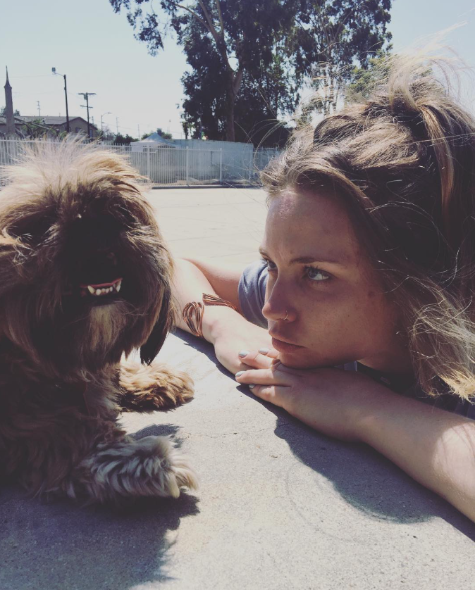 Daveigh Chase lies on the pavement beside a small dog in an August 6, 2016, photo shared on social media years before her death at 35 from complications related to meningitis and a blood infection. | Source: Instagram/daveighc