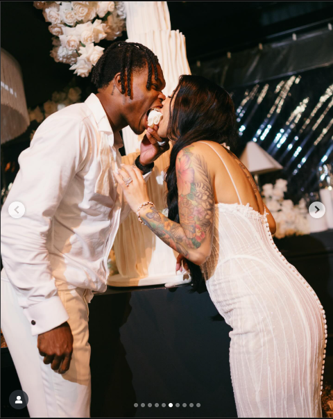 Travis Hunter and Leanna Lenee feed each other their wedding cake, dated May 2025 | Source: Instagram/db3_tip