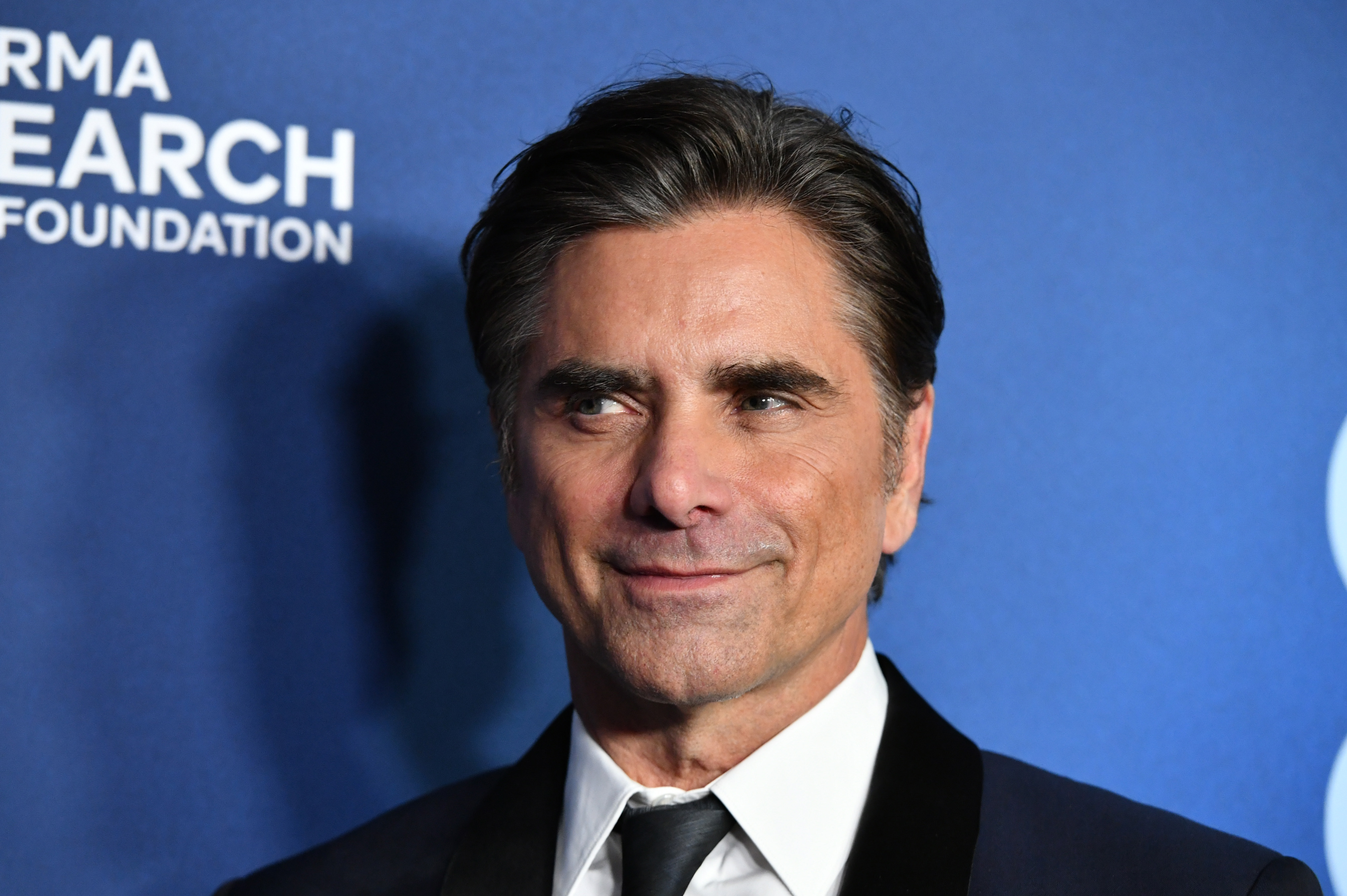 John Stamos brings timeless Hollywood style to the evening, wearing a classic black suit with satin lapels and swept-back hair. More than three decades after defining the cool charm and musical spirit of Uncle Jesse Katsopolis, the multitalented star continues to thrive across screen, stage, and voice roles, remaining an enduring fan favorite for multiple generations of viewers.