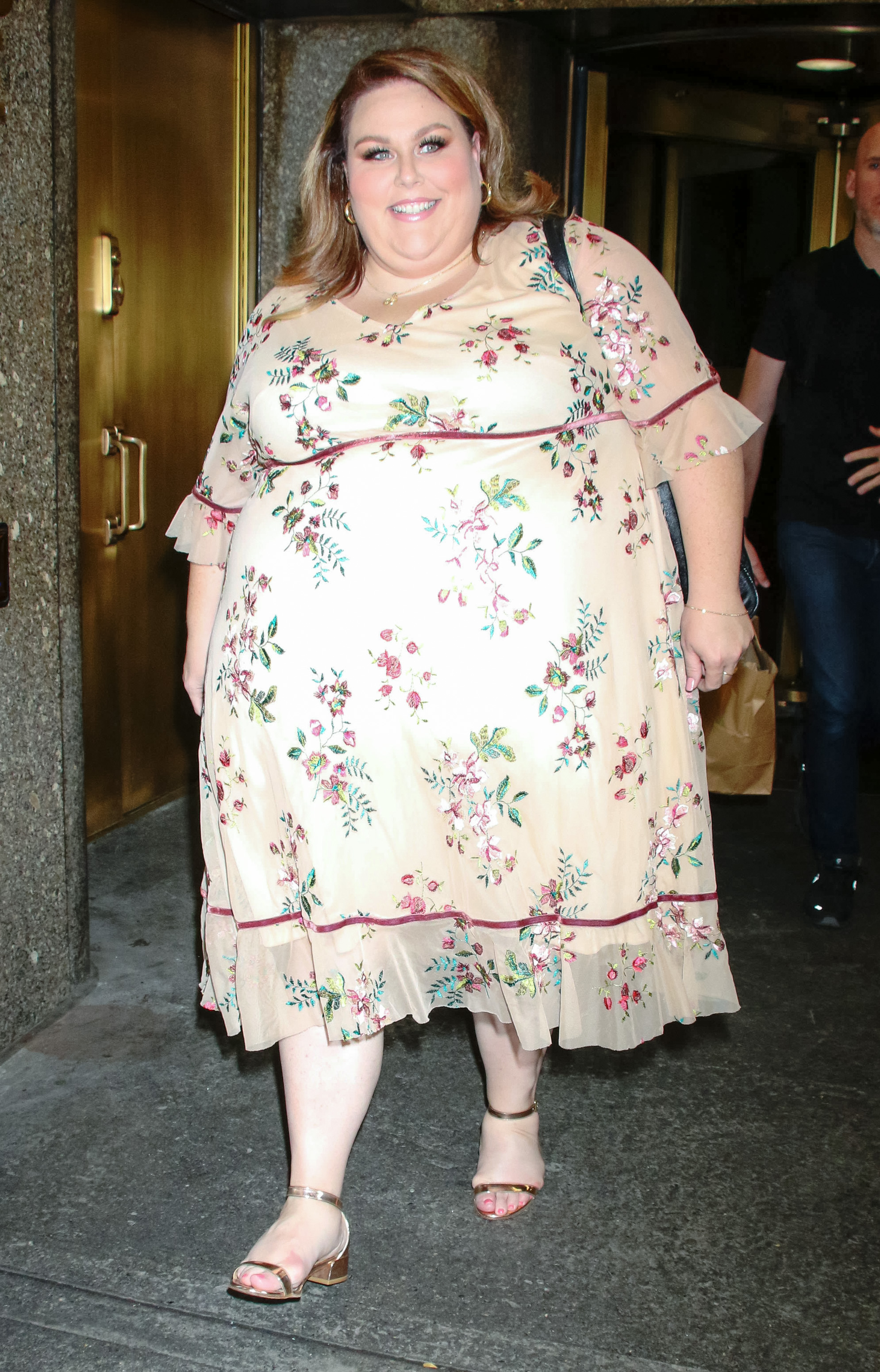 Metz was also photographed in New York wearing a light cream floral dress with pink and green prints. The street-style image provides a less formal look at her appearance during the same year.