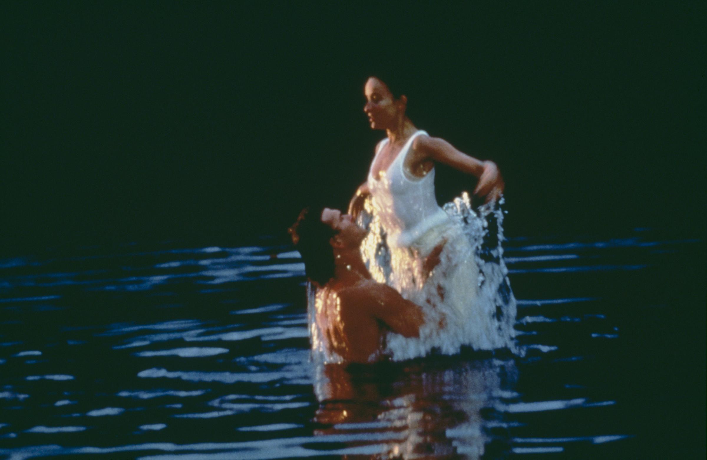 Johnny lifting Baby out of the water as she stares down at him. | Source: Getty Images