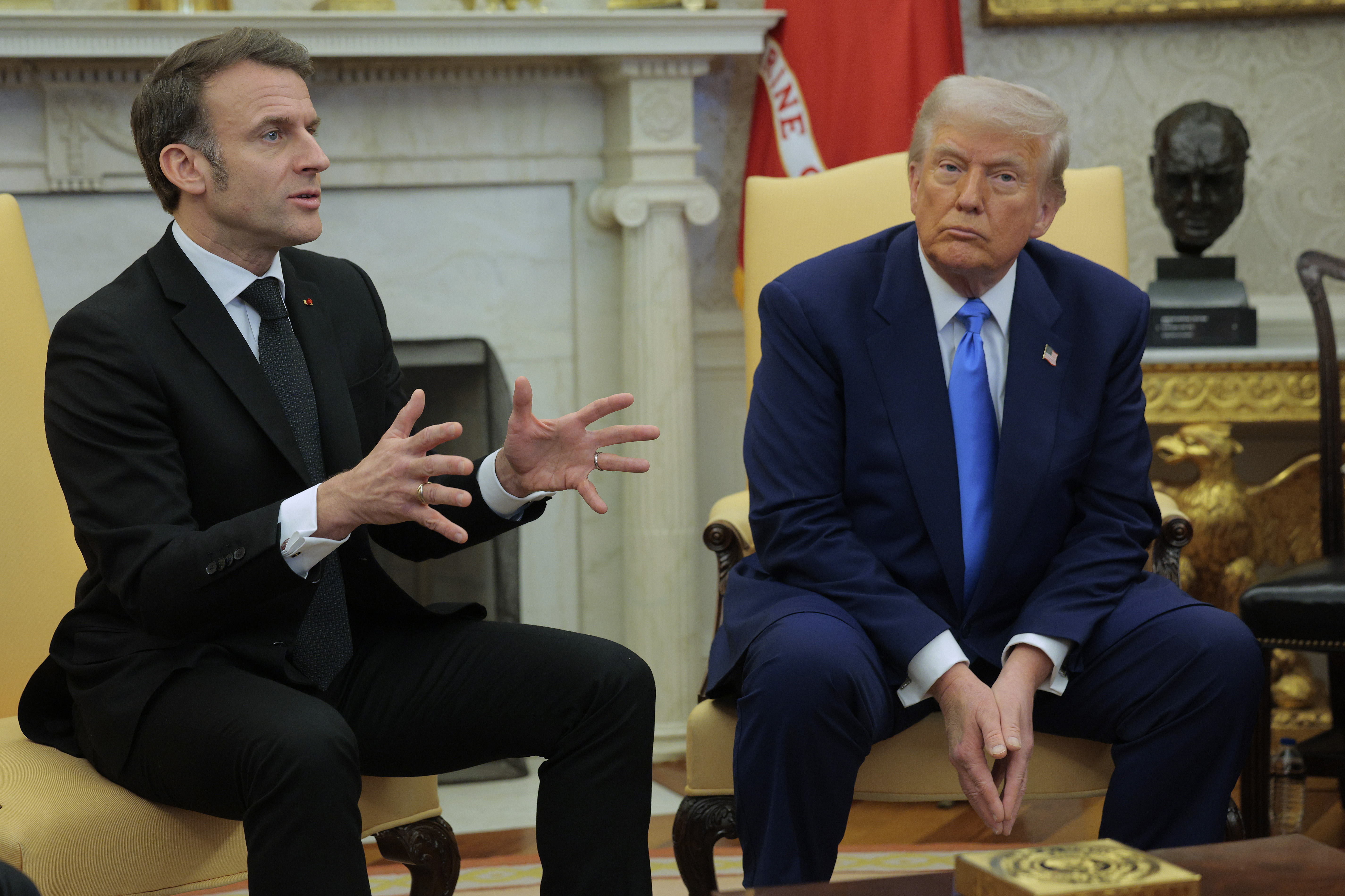 Donald Trump listens as French President Emmanuel Macron answers a reporter's question in the Oval Office at the White House in Washington, DC on February 24, 2025. | Source: Getty Images