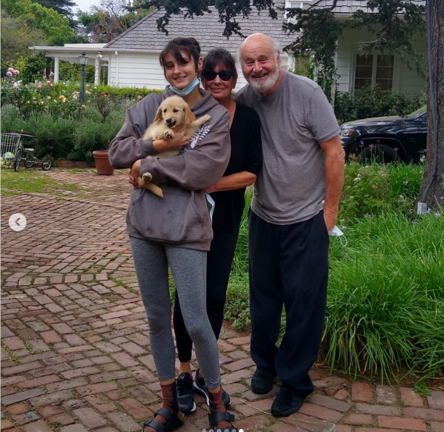 Romy Reiner stand together on a brick walkway in a lush garden setting outside a white house, from a post dated May 19, 2021. | Source: Instagram/romyreiner